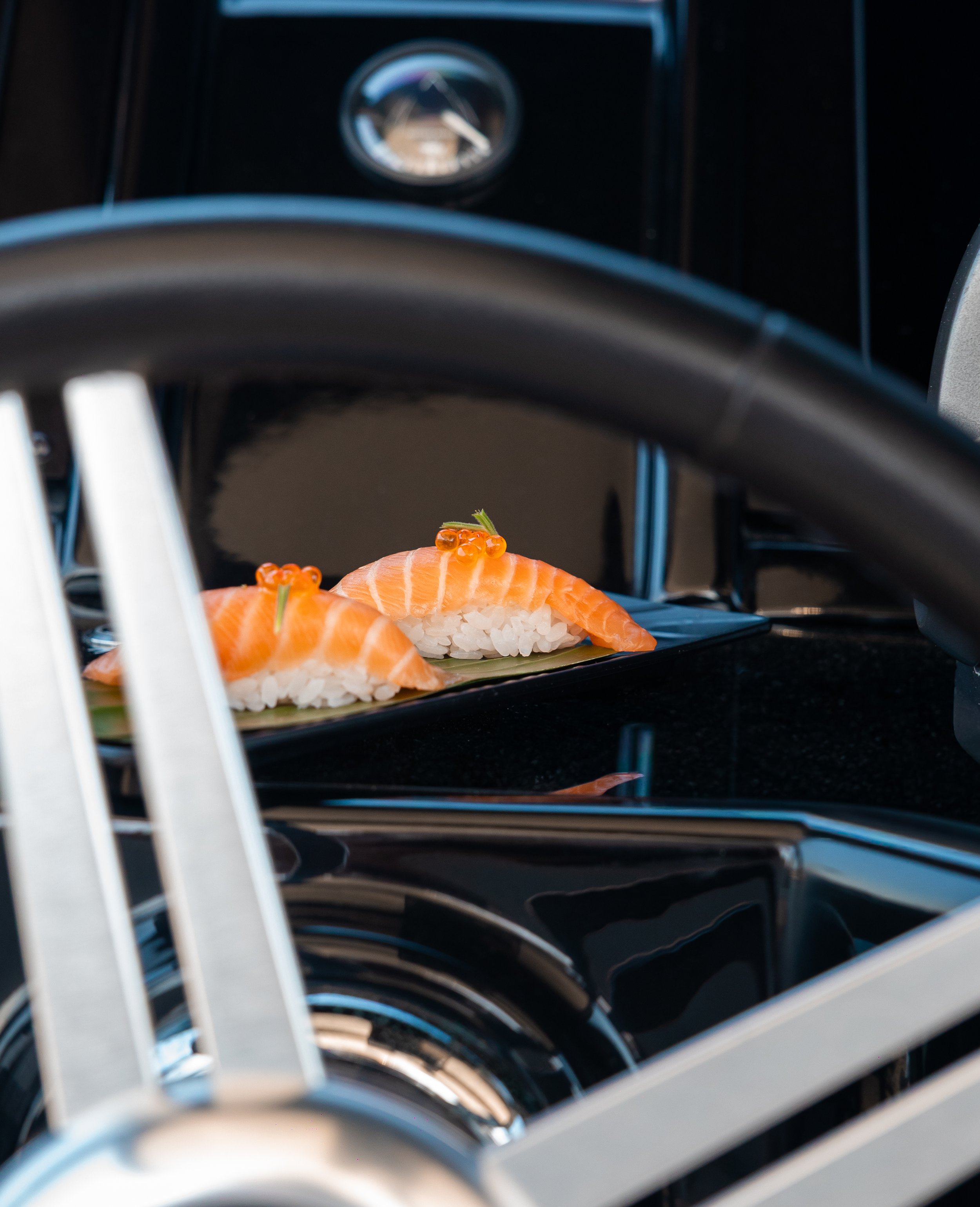 Close-up of a modern black coffee maker, with a small, orange fish gently placed on a piece of white rice inside the coffee maker.