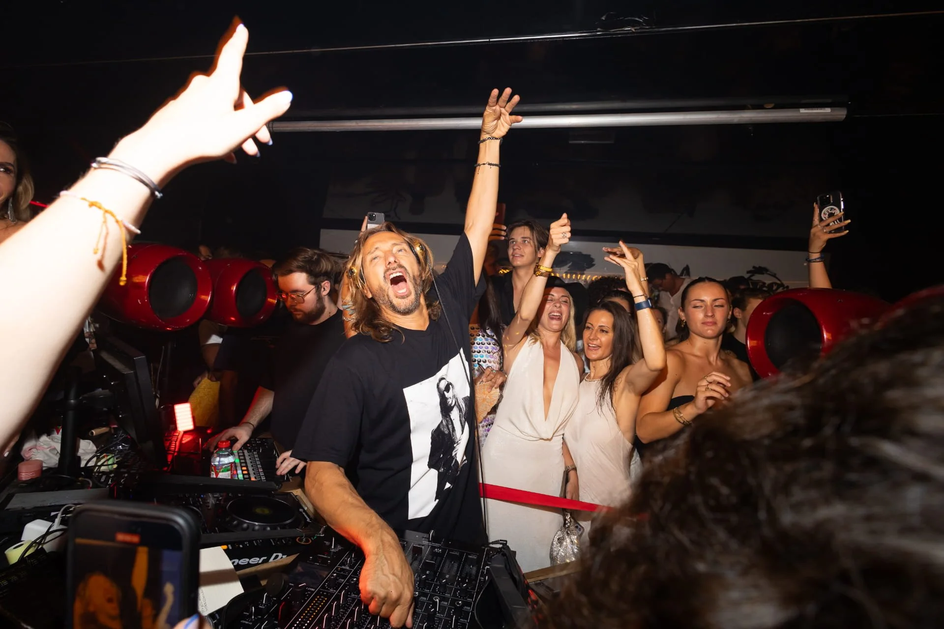 DJ playing music at a lively party with women dancing and celebrating.