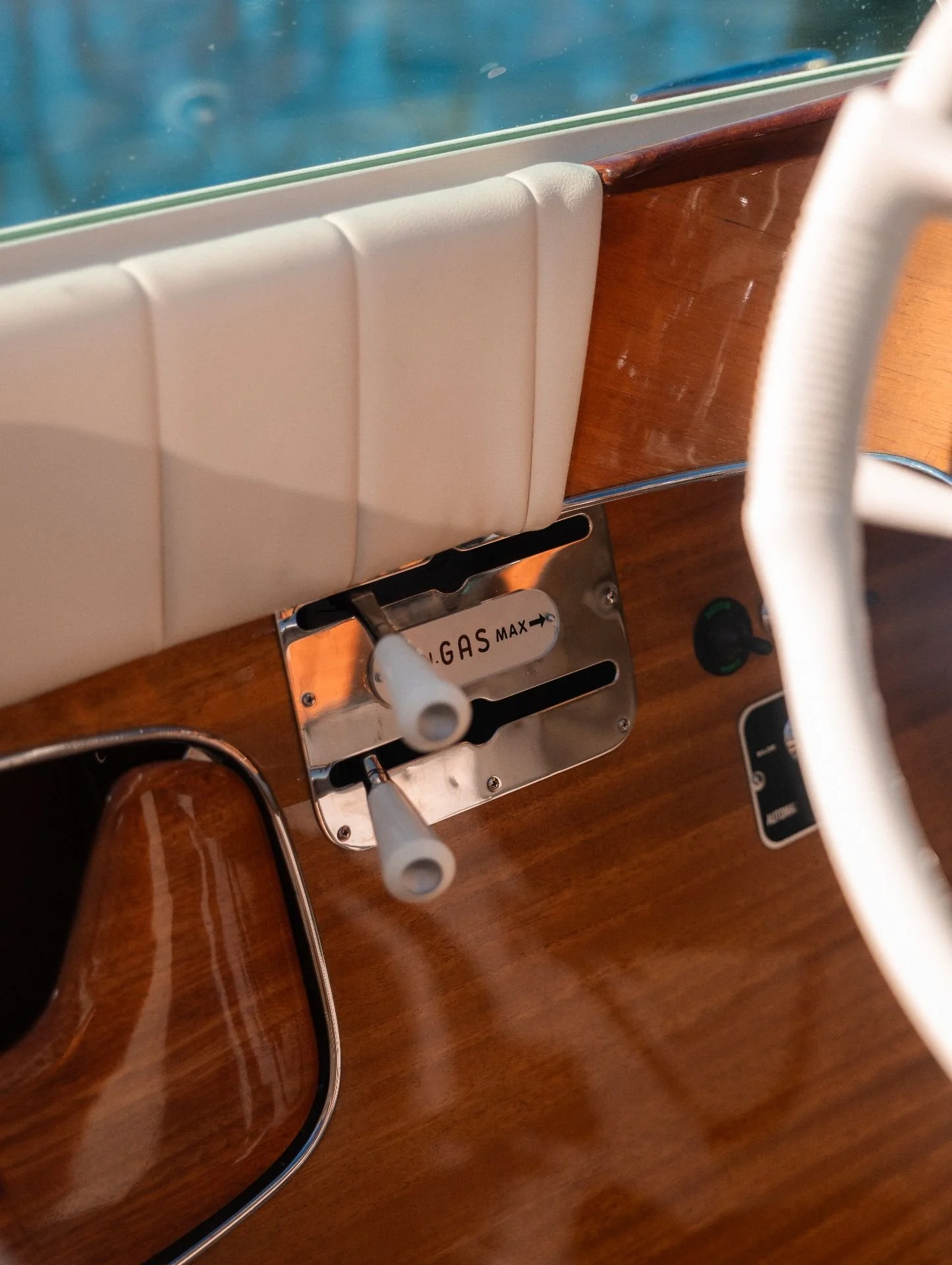 Close-up of a wooden surface with a white leather padded headrest, a metal gas valve labeled "GAS MAX," and a shoe at the bottom left corner.