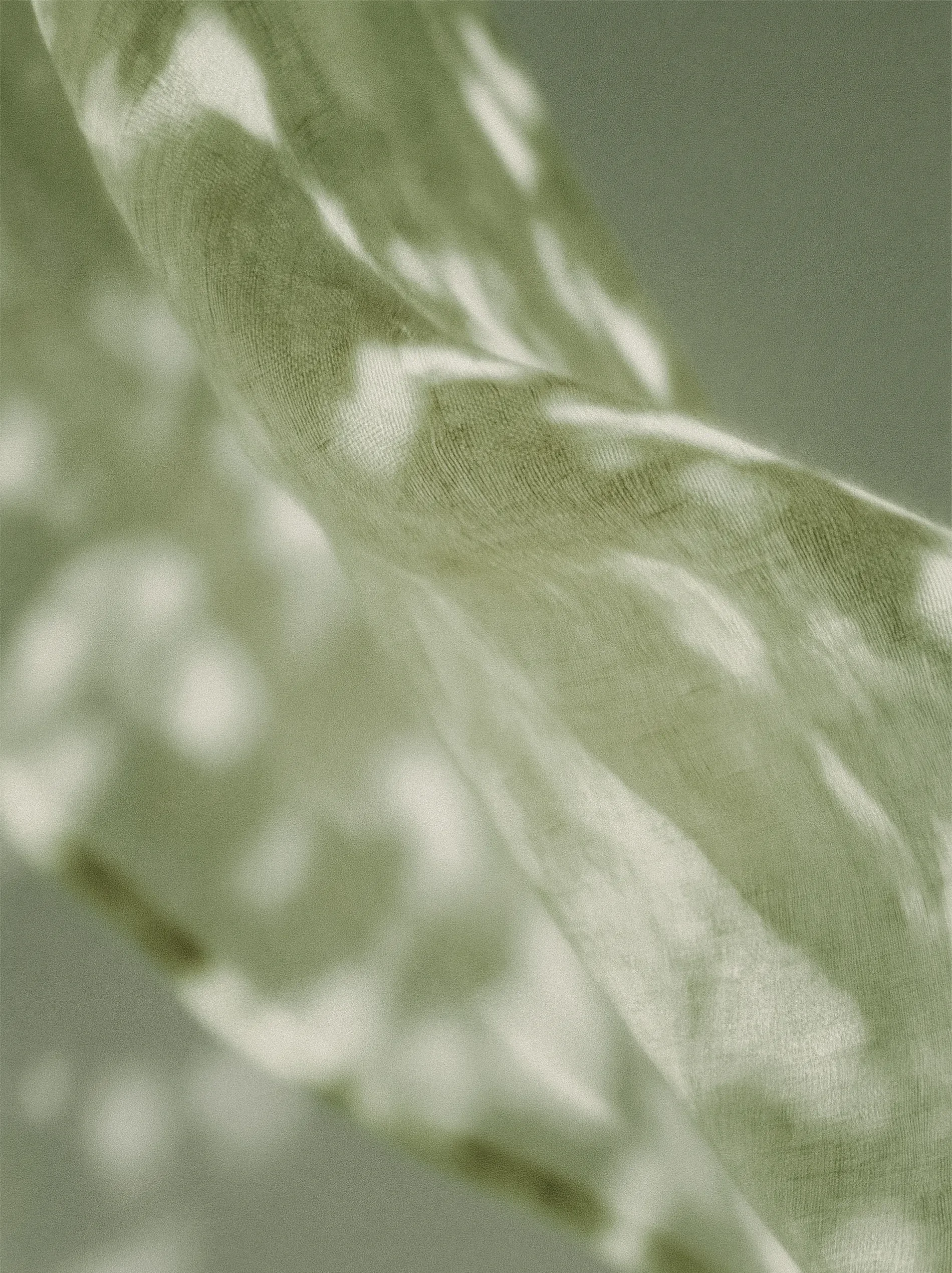 A close-up of fabric with a soft, textured weave, in a pale green color.