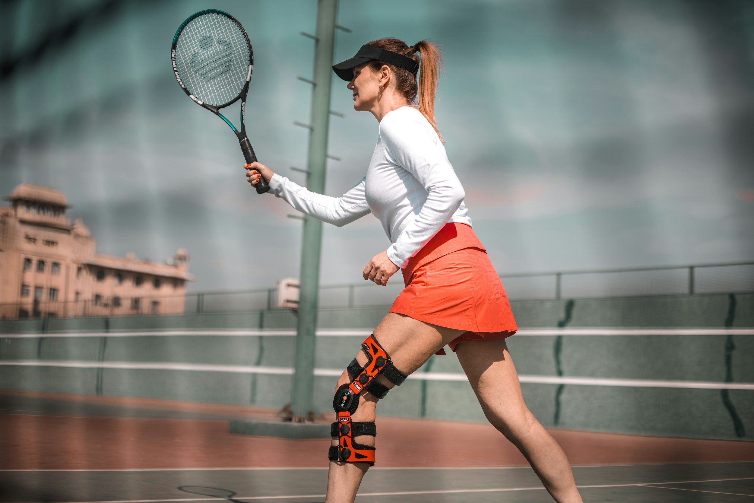 A woman playing tennis wearing a knee brace for the management of an acute or chronic or post operative knee injury
