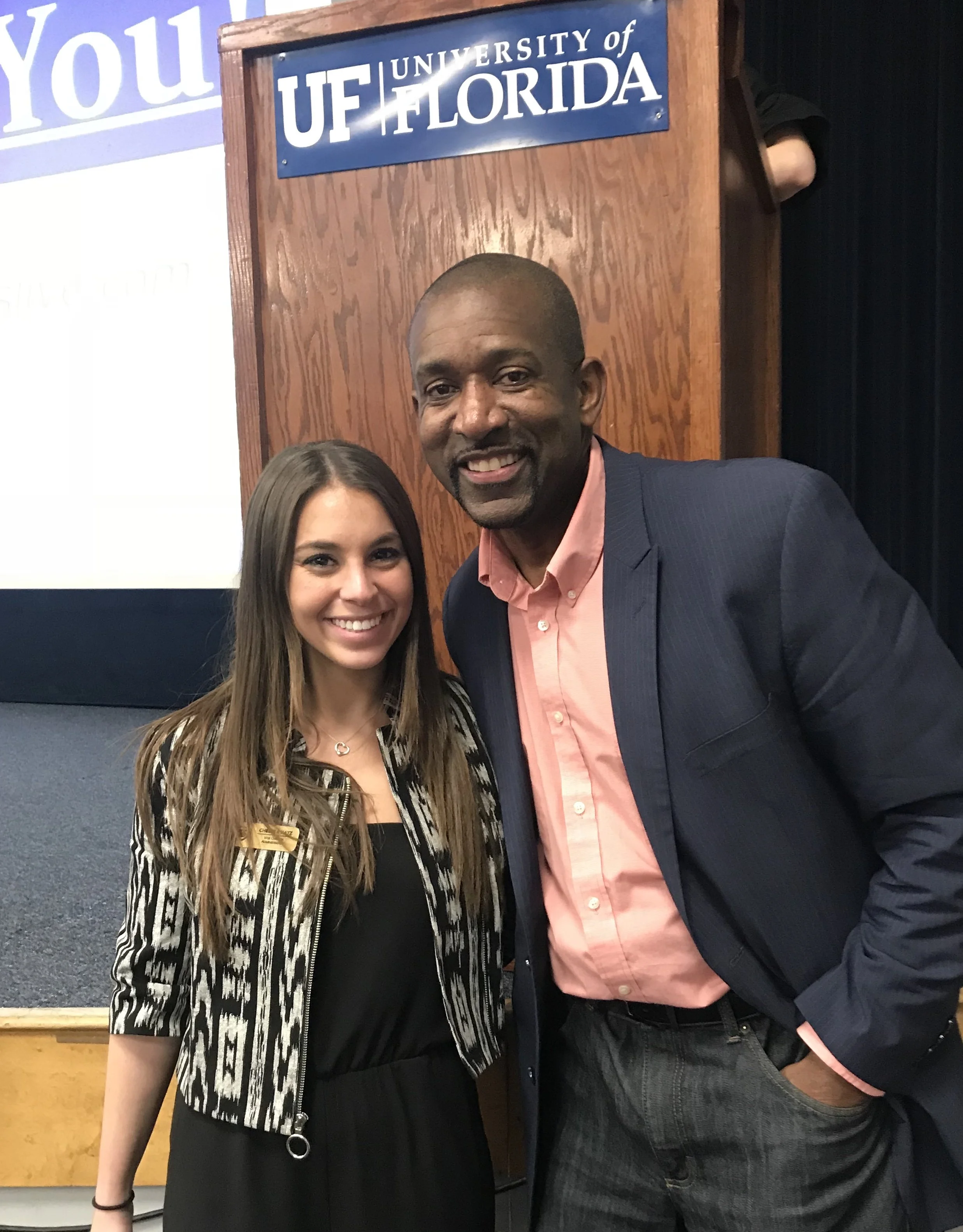 Young woman and man smiling at an event with a University of Florida sign in the background.