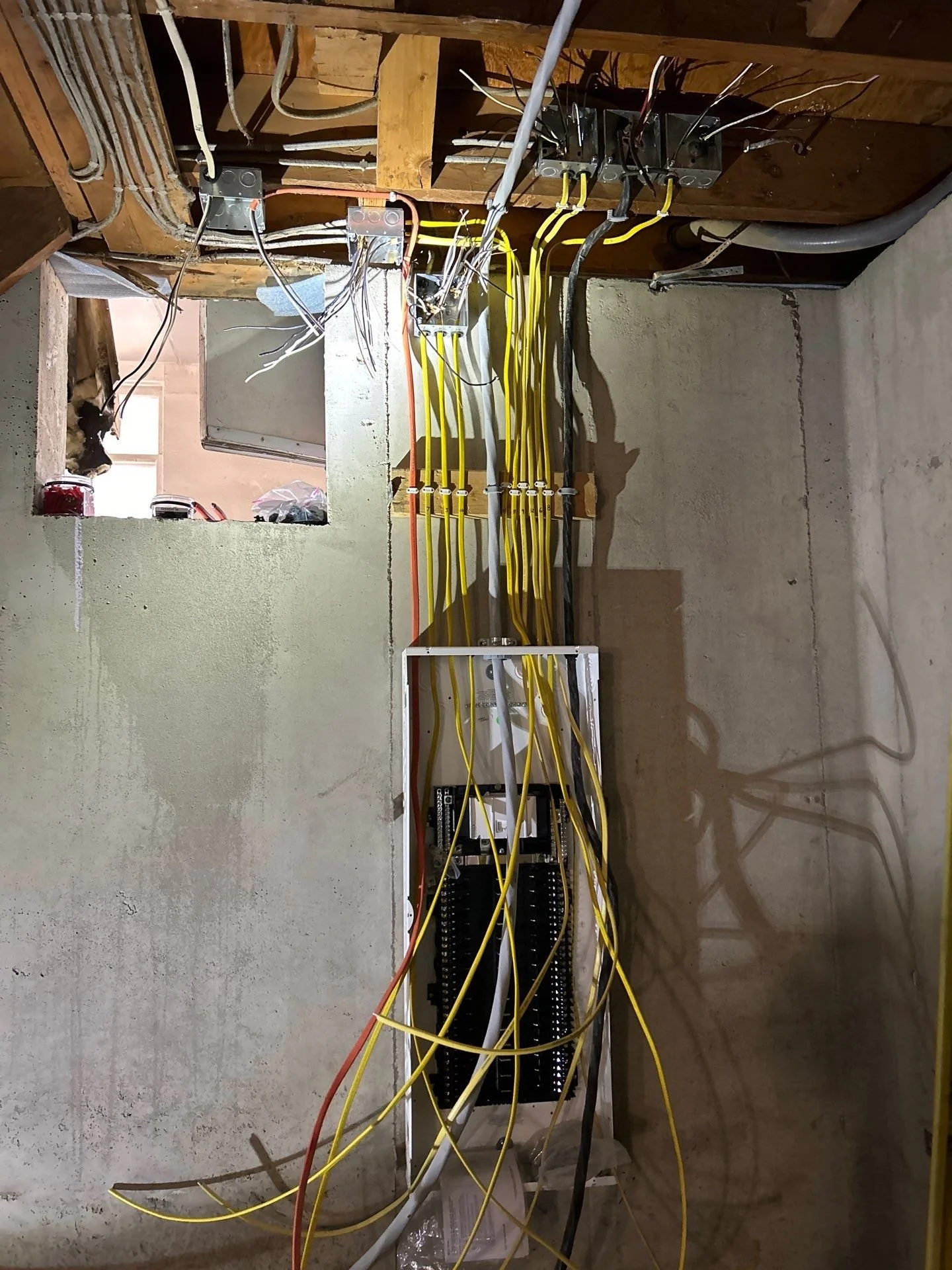 Electrical wiring and panels installed inside a building under construction, with exposed wood beams and unfinished walls.