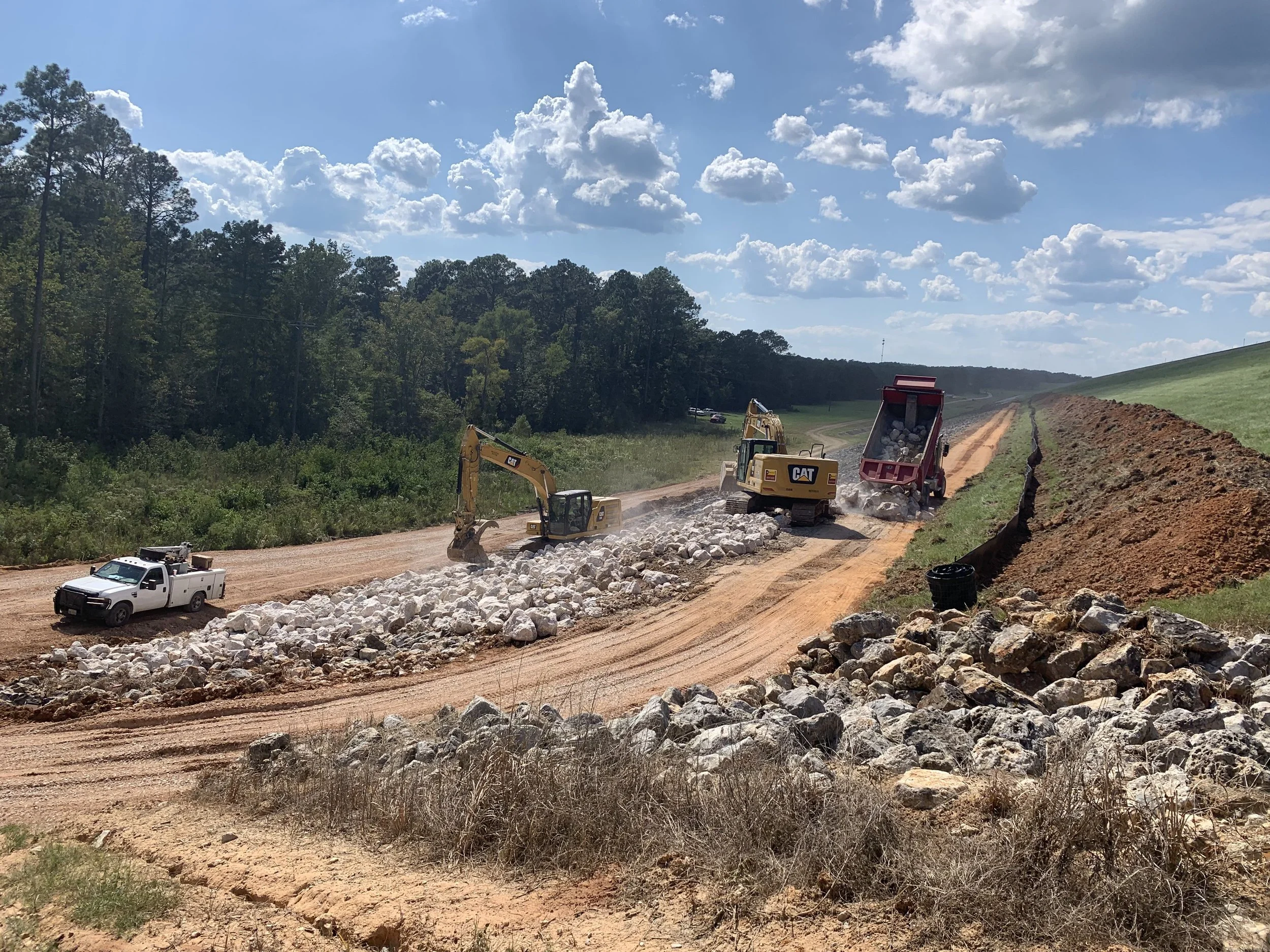 Hippos Construction heavy equipment performing rip-rap installation and erosion control grading in Hutto, Texas.