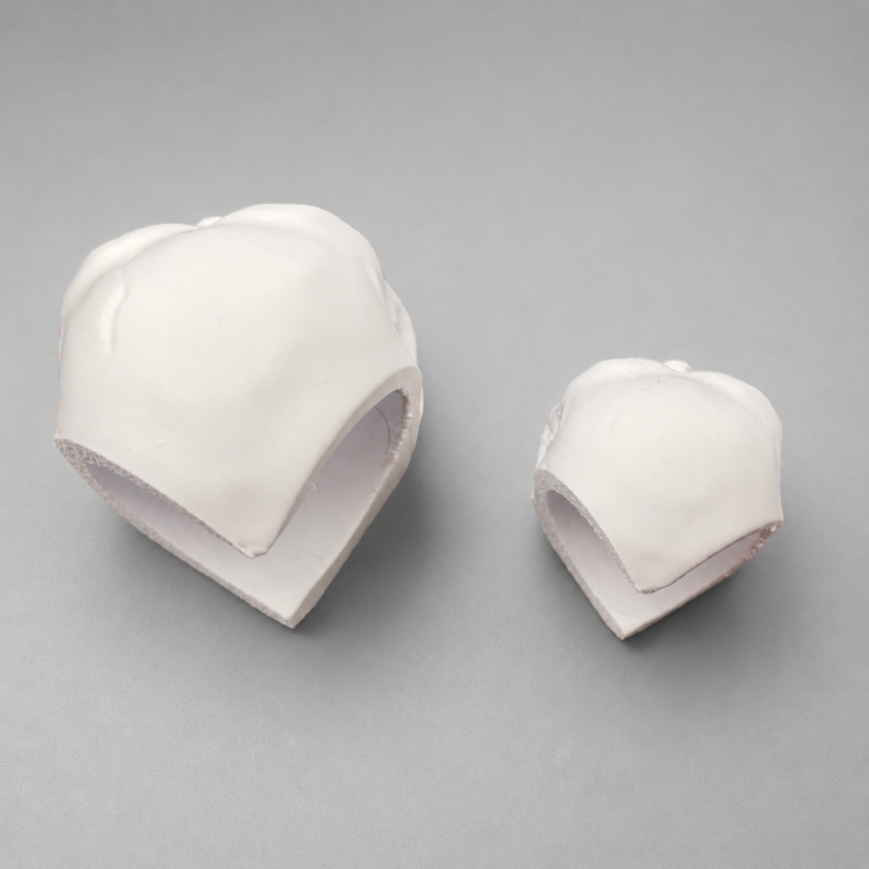 Rear view of large and small 3D printed Corner Skull hides showing the cutaway shape designed to fit into an enclosure corner.
