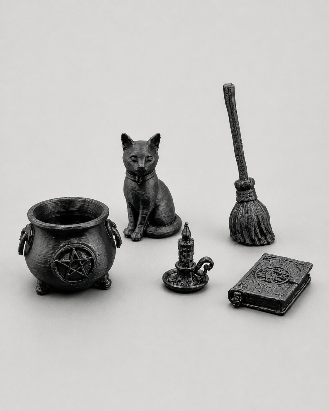 Angled view of The Witch’s Essentials miniature 3D printed witch accessory set featuring a cauldron, cat, broom, candle and spellbook.