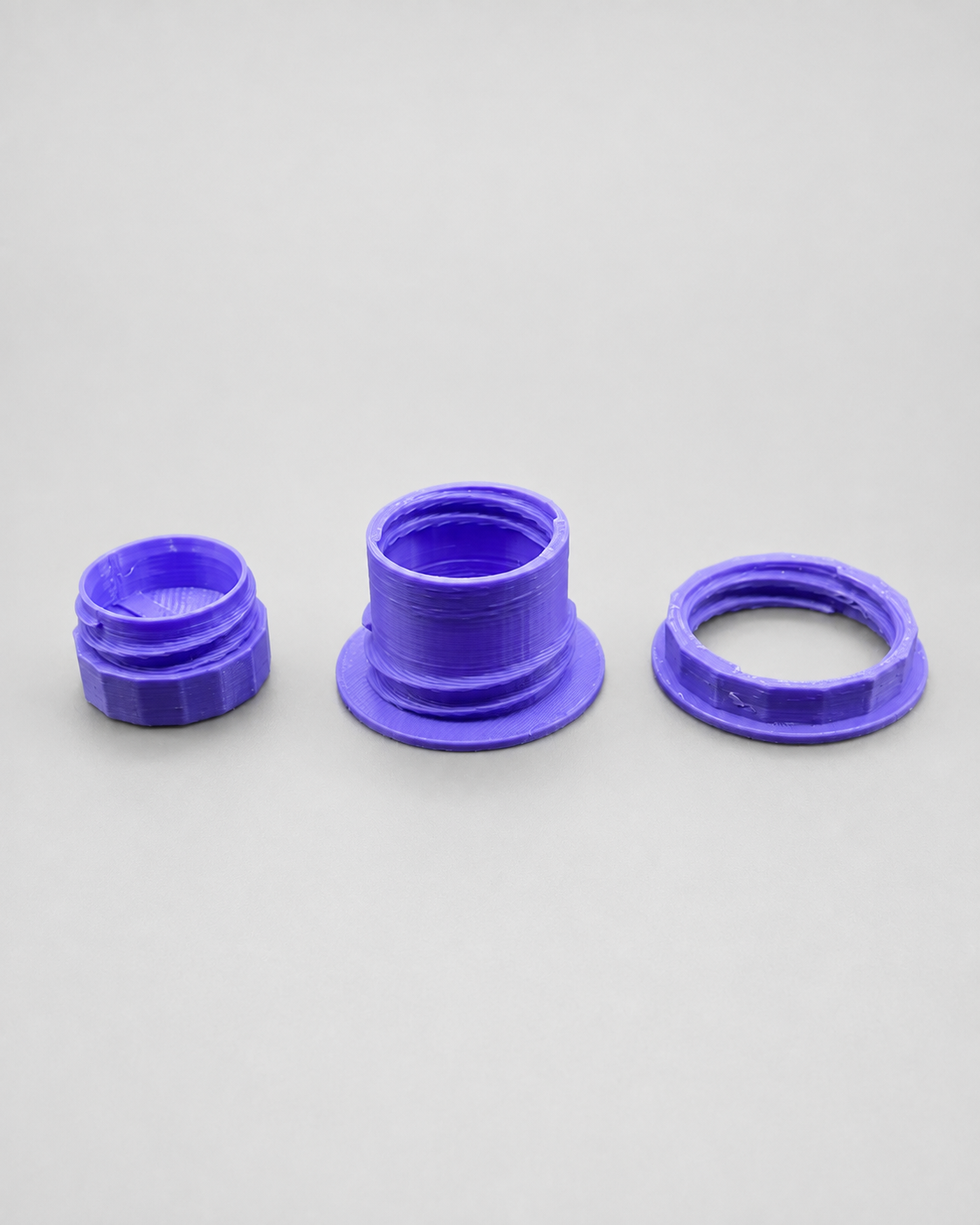 Three components of The Fly Tap 3D printed fruit fly culture dispenser including upper and lower lid mounts and removable screw-on cap.