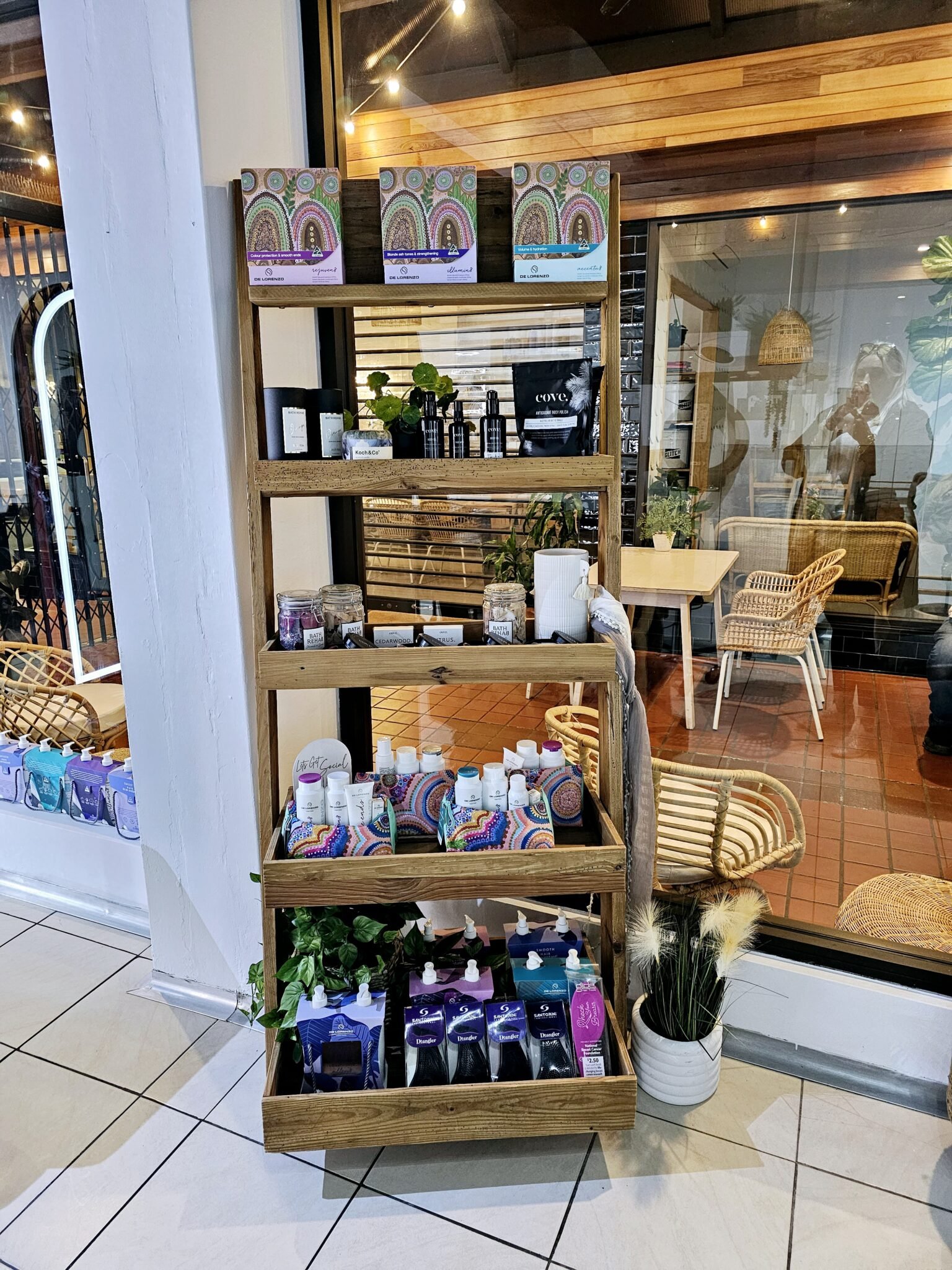Display shelf with health and wellness products in a store, behind a glass window with reflection of the interior, including seating area and a person taking a photo.