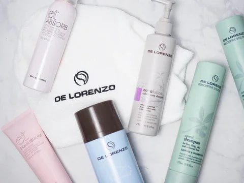 Collection of De Lorenzo hair care products including shampoo, conditioner, and treatments, arranged on a white marble surface.
