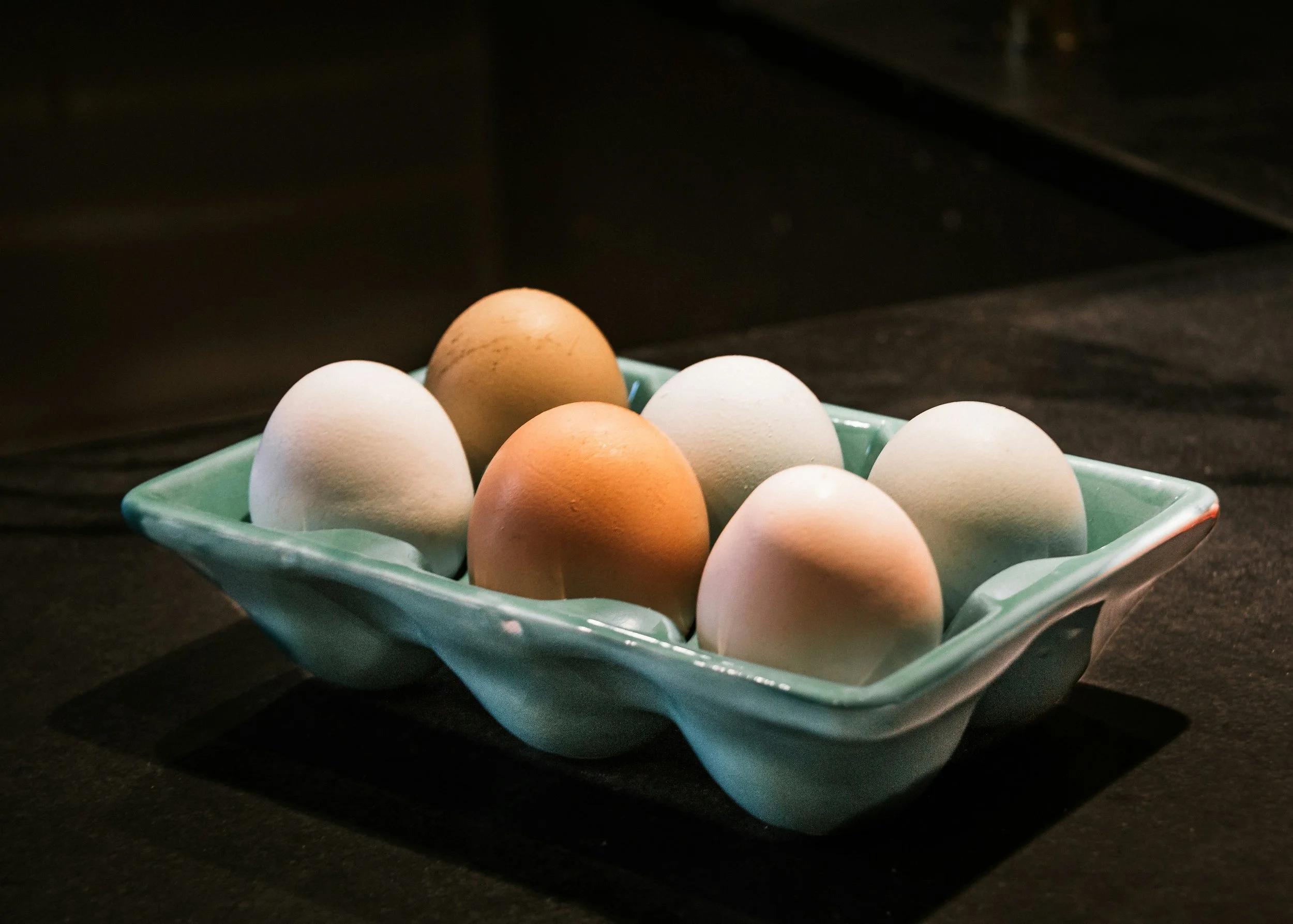 A tray of white and brown eggs on a dark countertop.