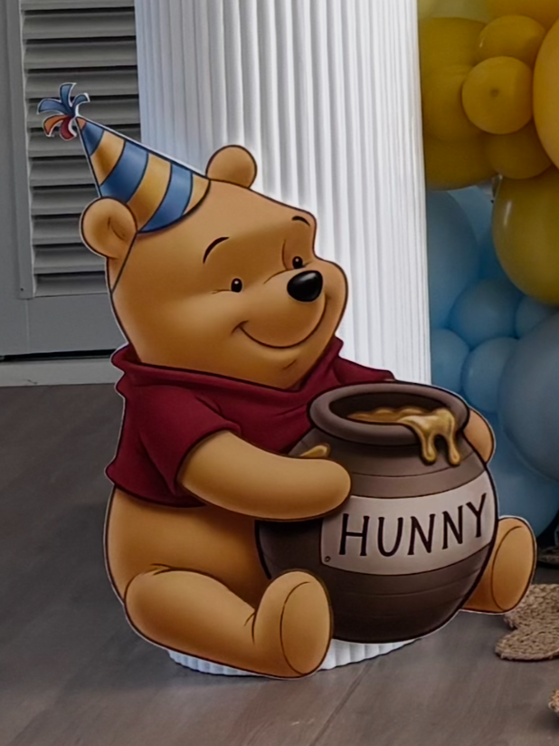 Cartoon of Winnie the Pooh wearing a birthday hat and holding a pot of honey labeled 'HUNNY'.