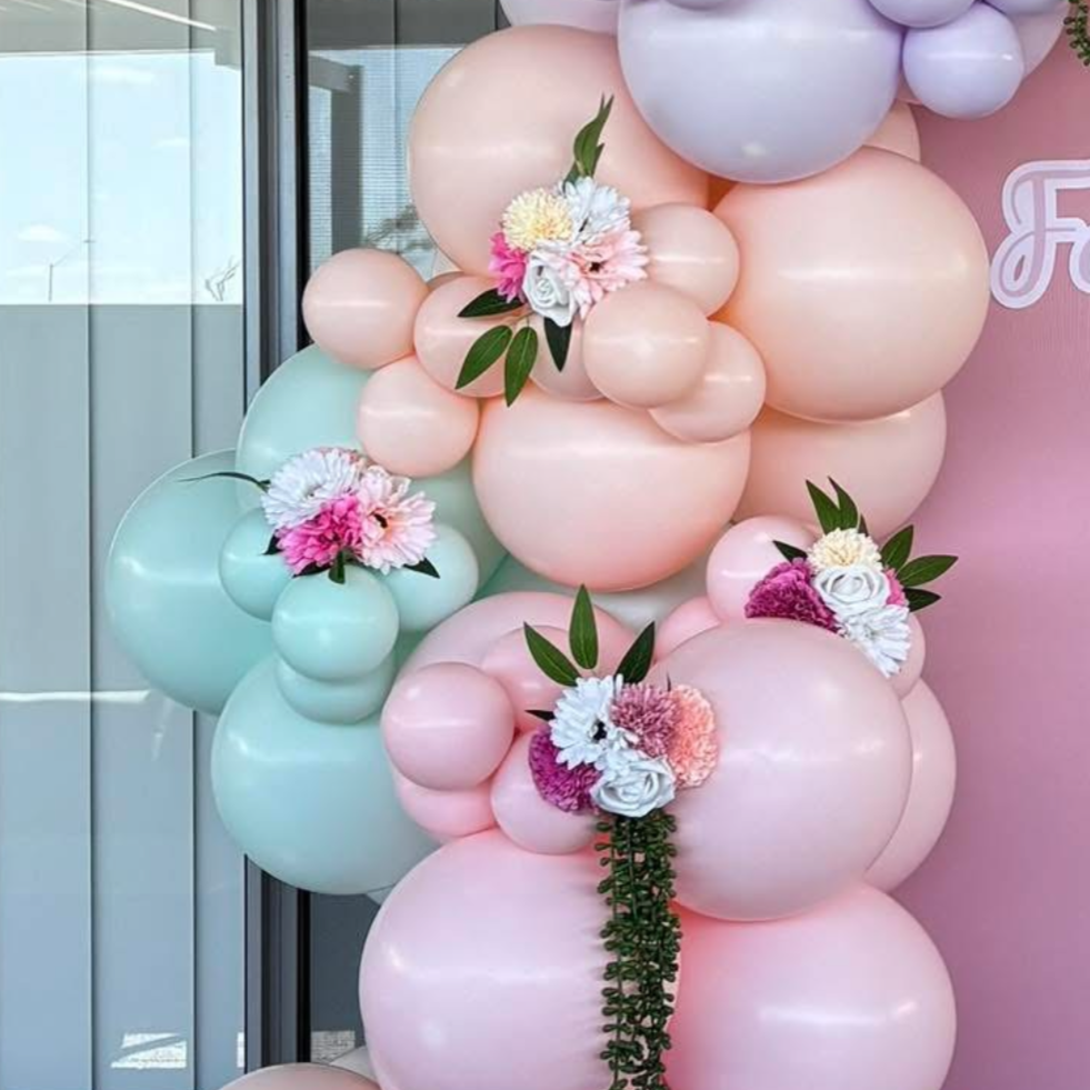 Balloon arrangement with pastel pink, mint green, and lavender balloons decorated with flowers and green leaves.