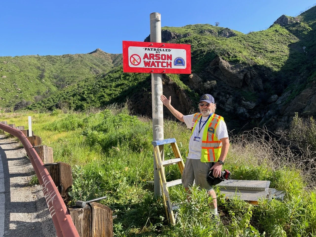 Arson Watch volunteer installing a “Patrolled by Arson Watch” sign