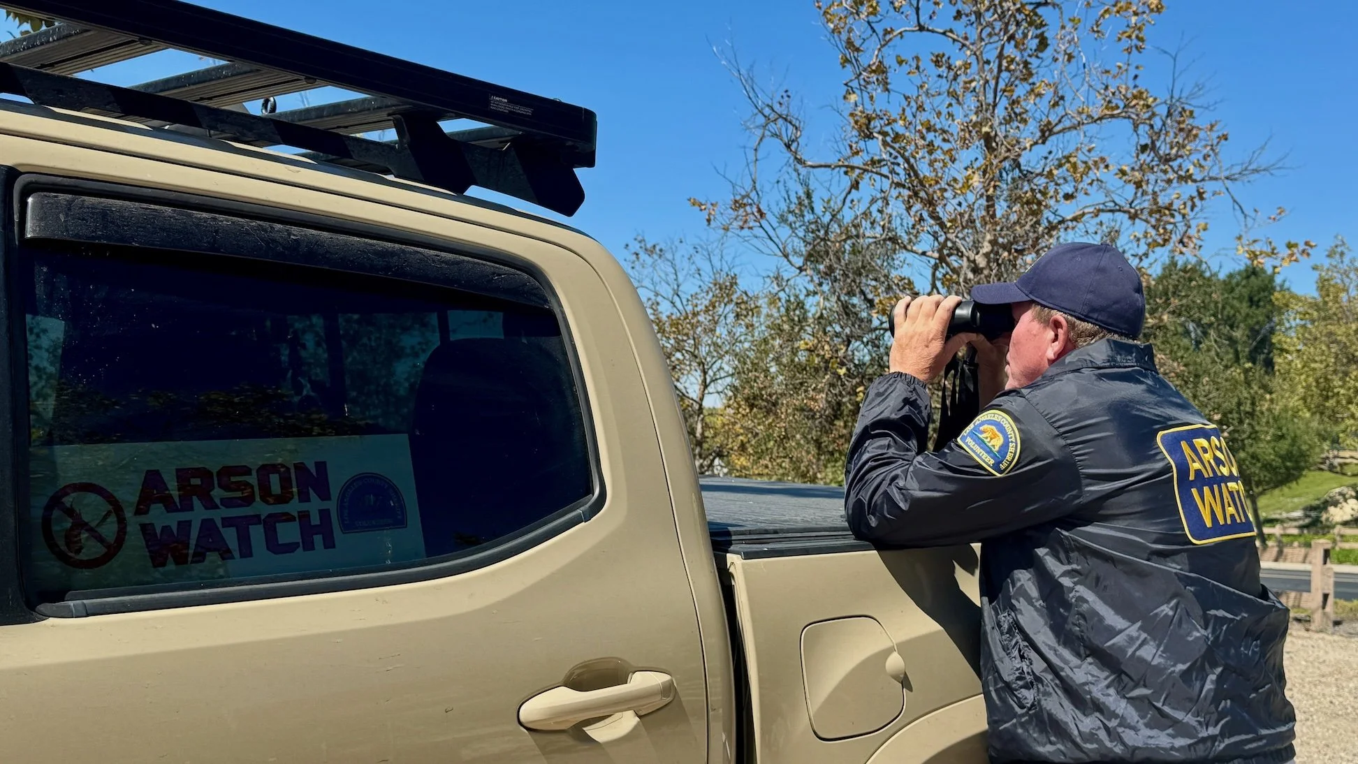Arson Watch member on patrol looking across the mountains through binoculars 