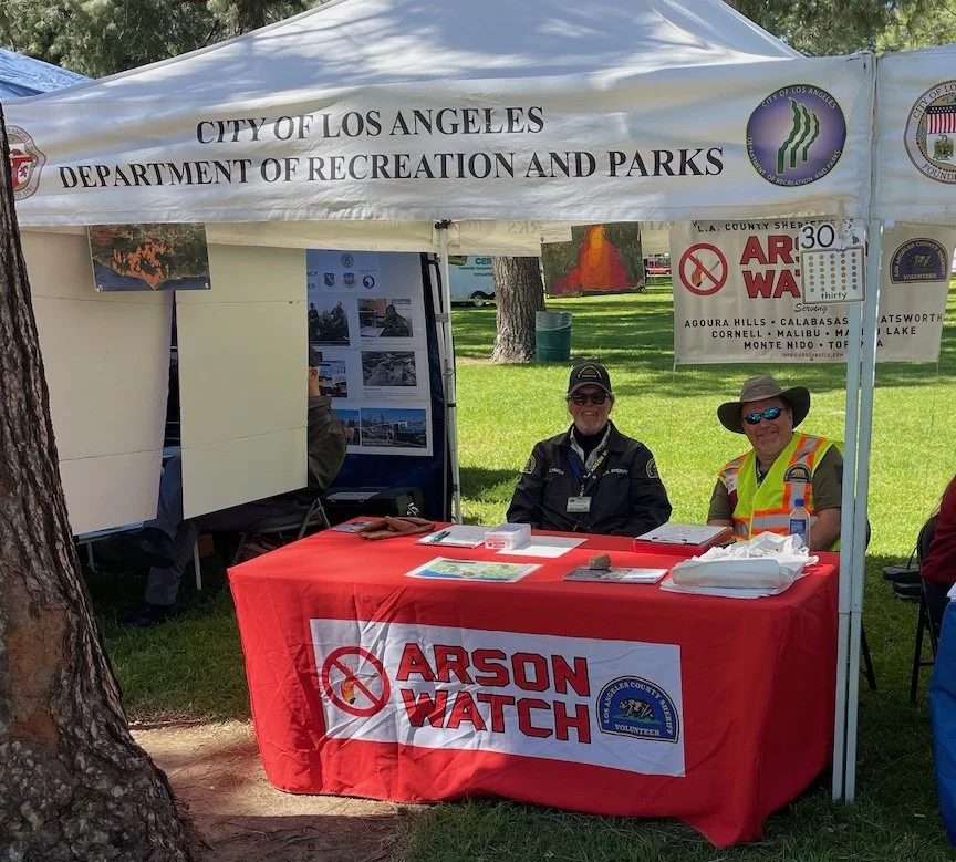 Arson Watch members sitting in an Arson Watch booth at a local safety fair