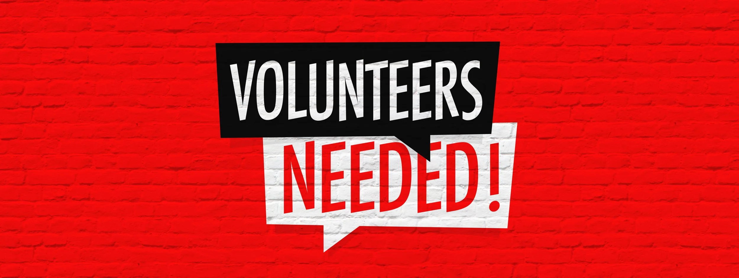Volunteers Needed graphic painted on a brick wall by Brad Pict