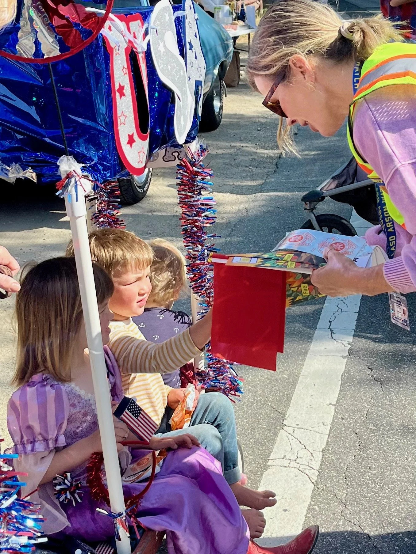 An Arson Watch member handing out red flags to a  group of young children sitting on a bench during the Topanga Days parade