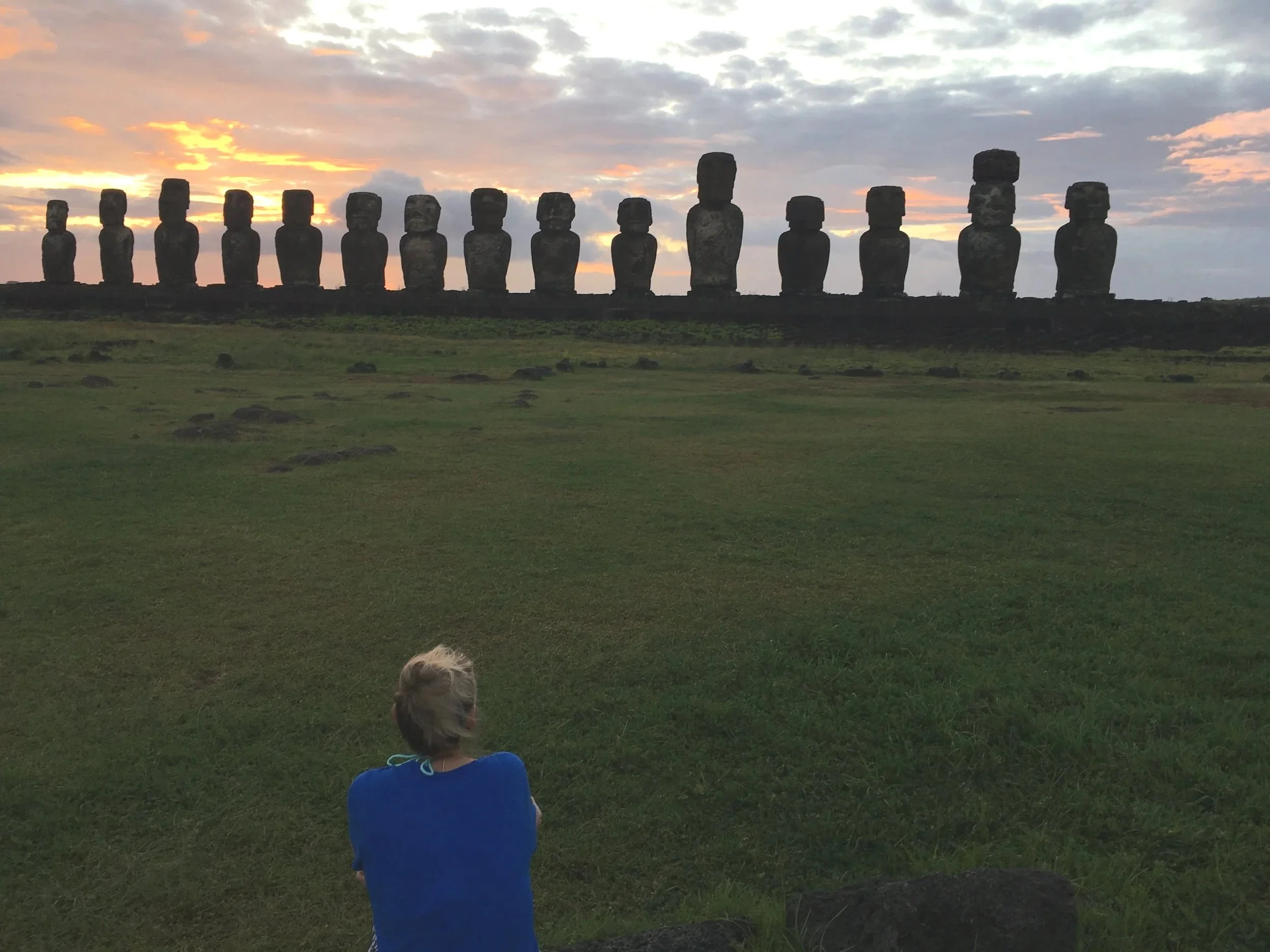 A woman watching the moai statues at Ahu Tongariki during sunrise on Easter Island.