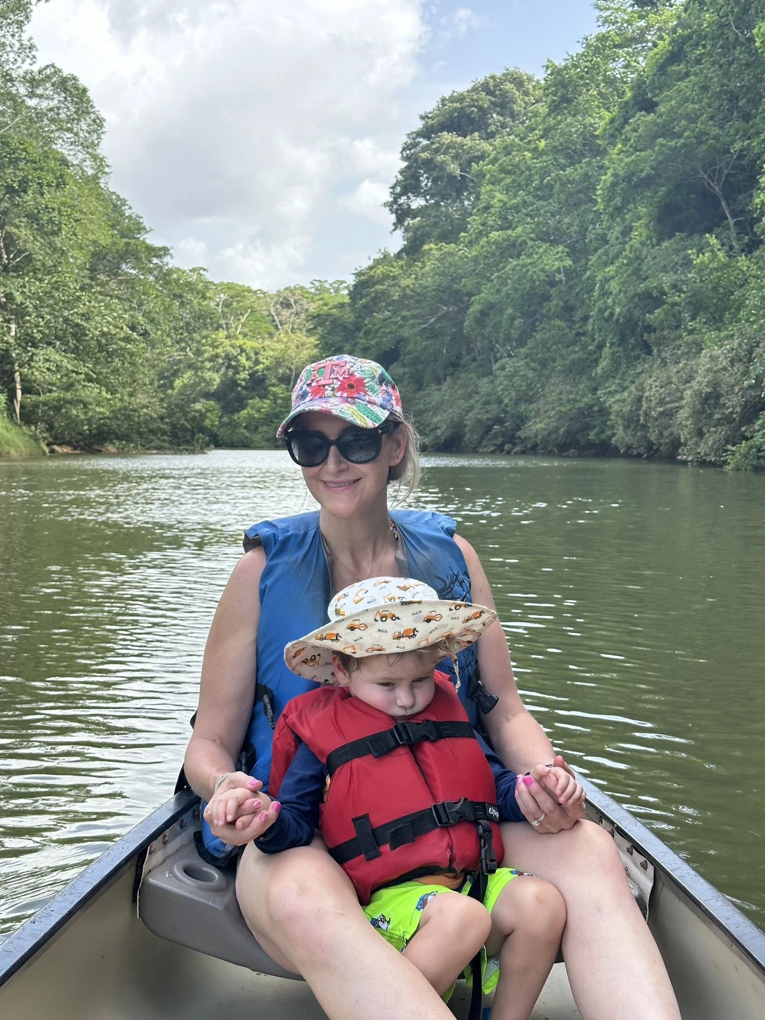 A woman and child canoeing on a tree-lined river near San Ignacio, Belize.
