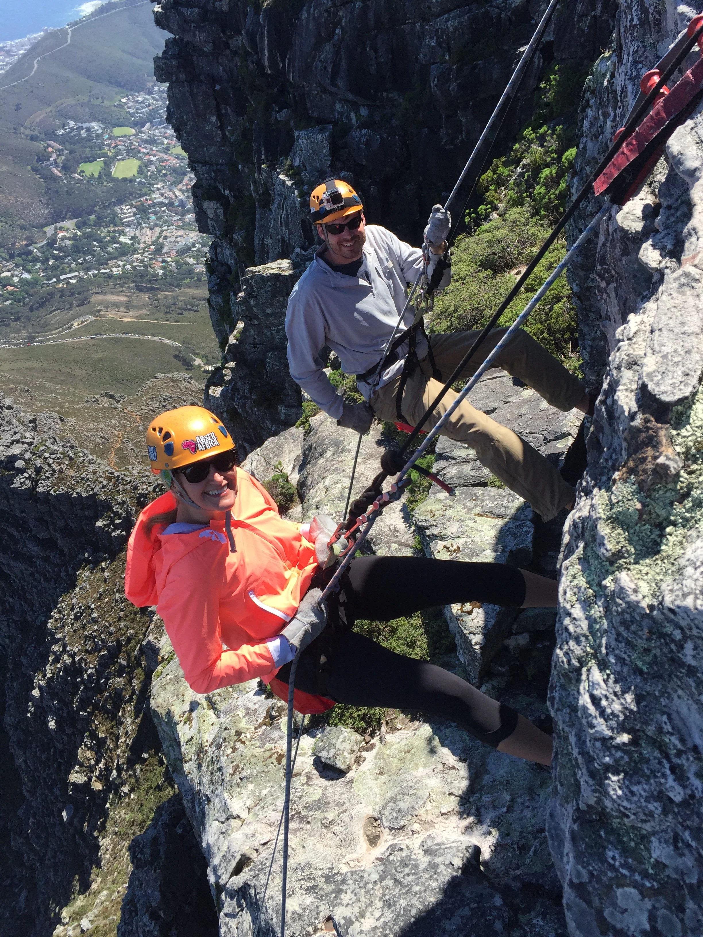 Two people abseiling down the rocky face of Table Mountain.
