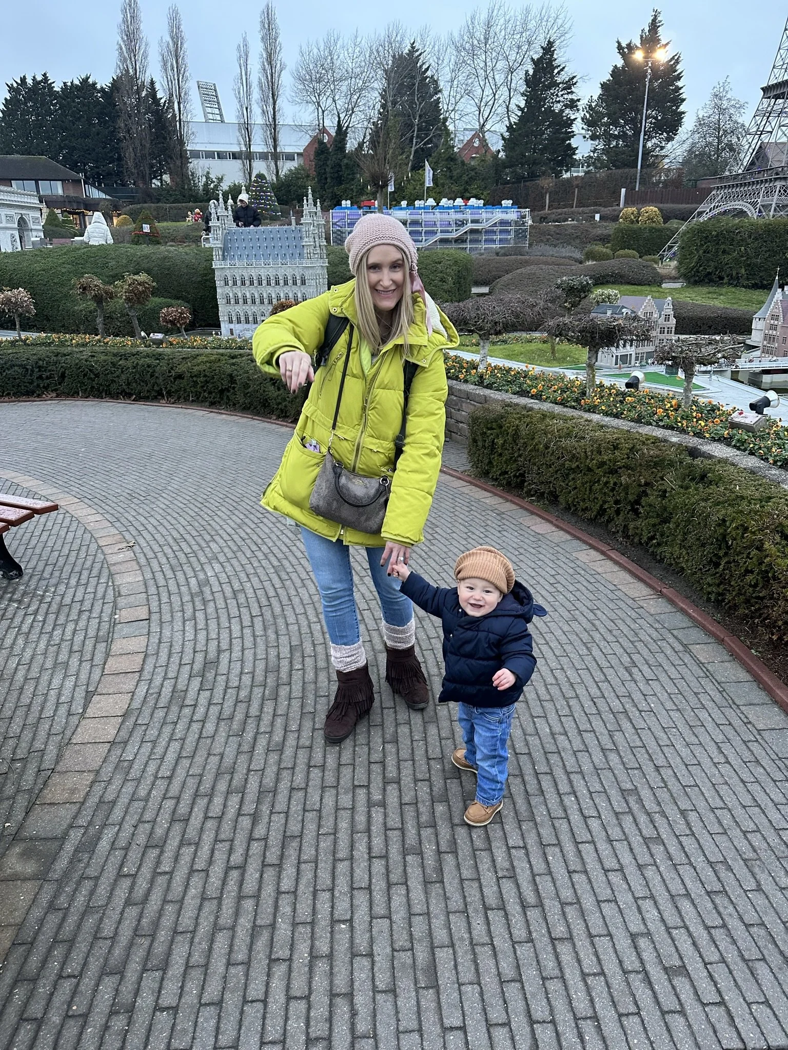 Woman holding a young boy’s hand beside miniature landmarks at Mini-Europe in Brussels.