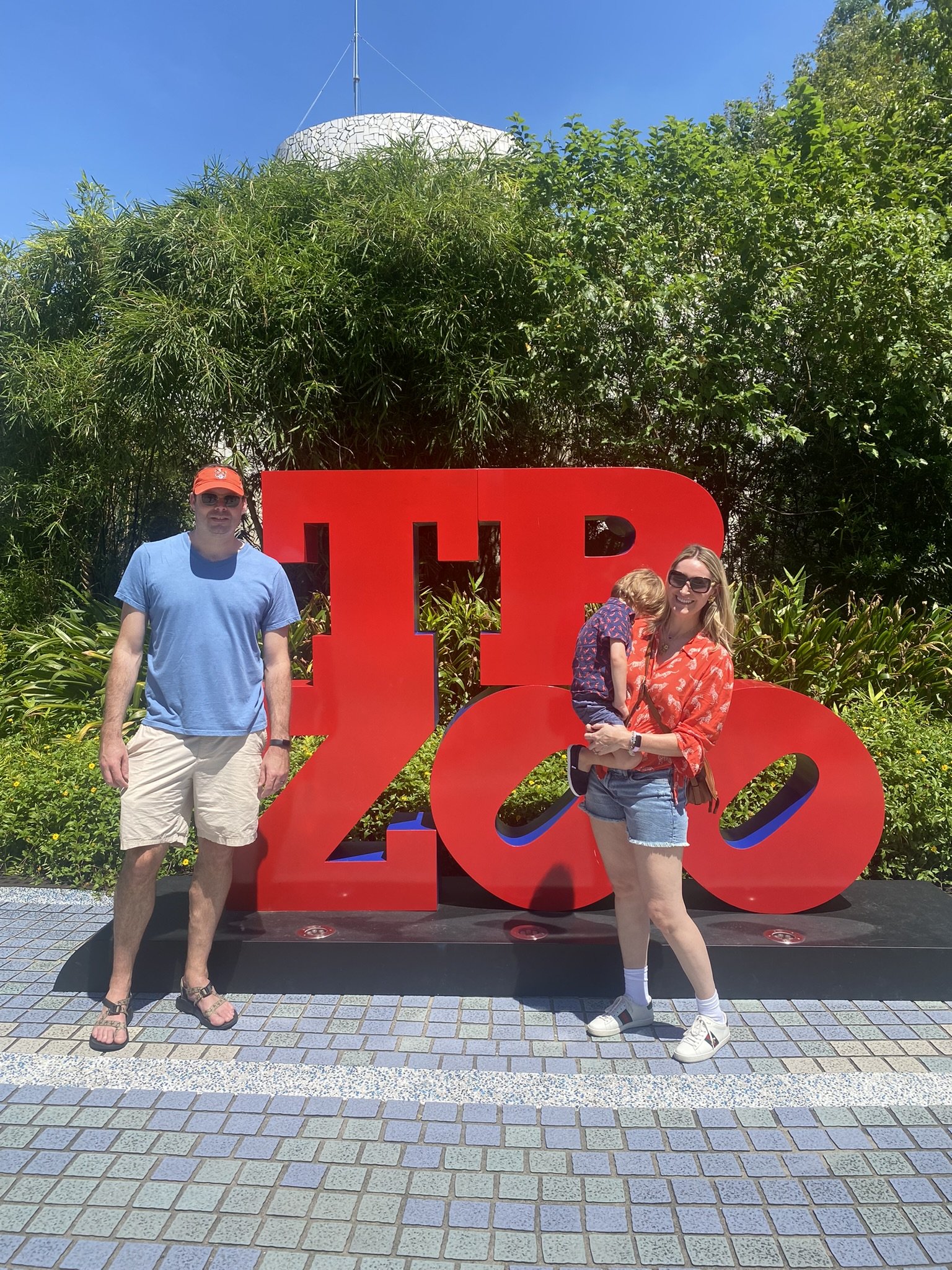Two adults and a child posing beside a large red sculpture at Taipei Zoo.