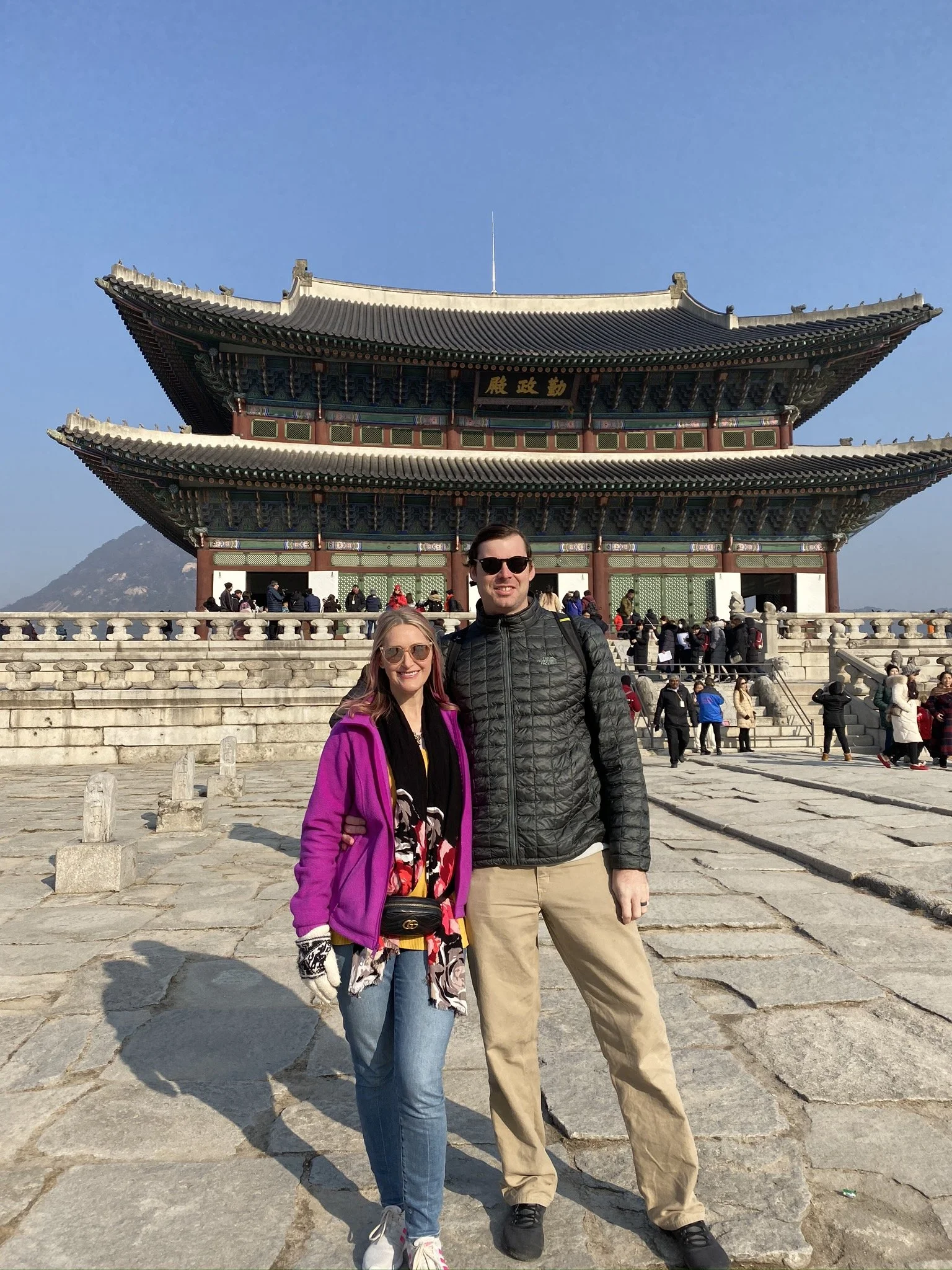 Two people standing in front of a traditional temple in Seoul, South Korea.
