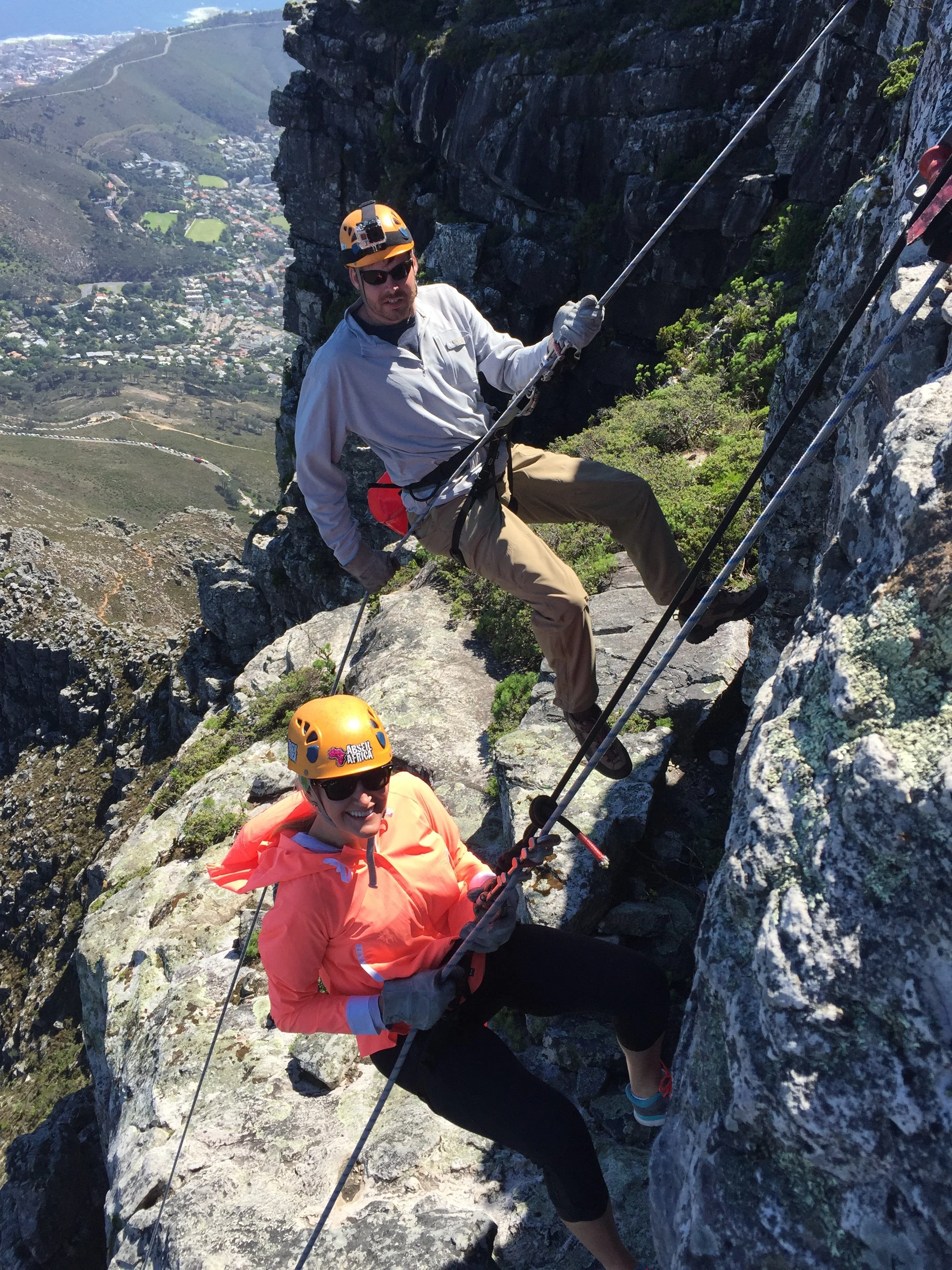 Two people abseiling down Table Mountain above Cape Town, South Africa.