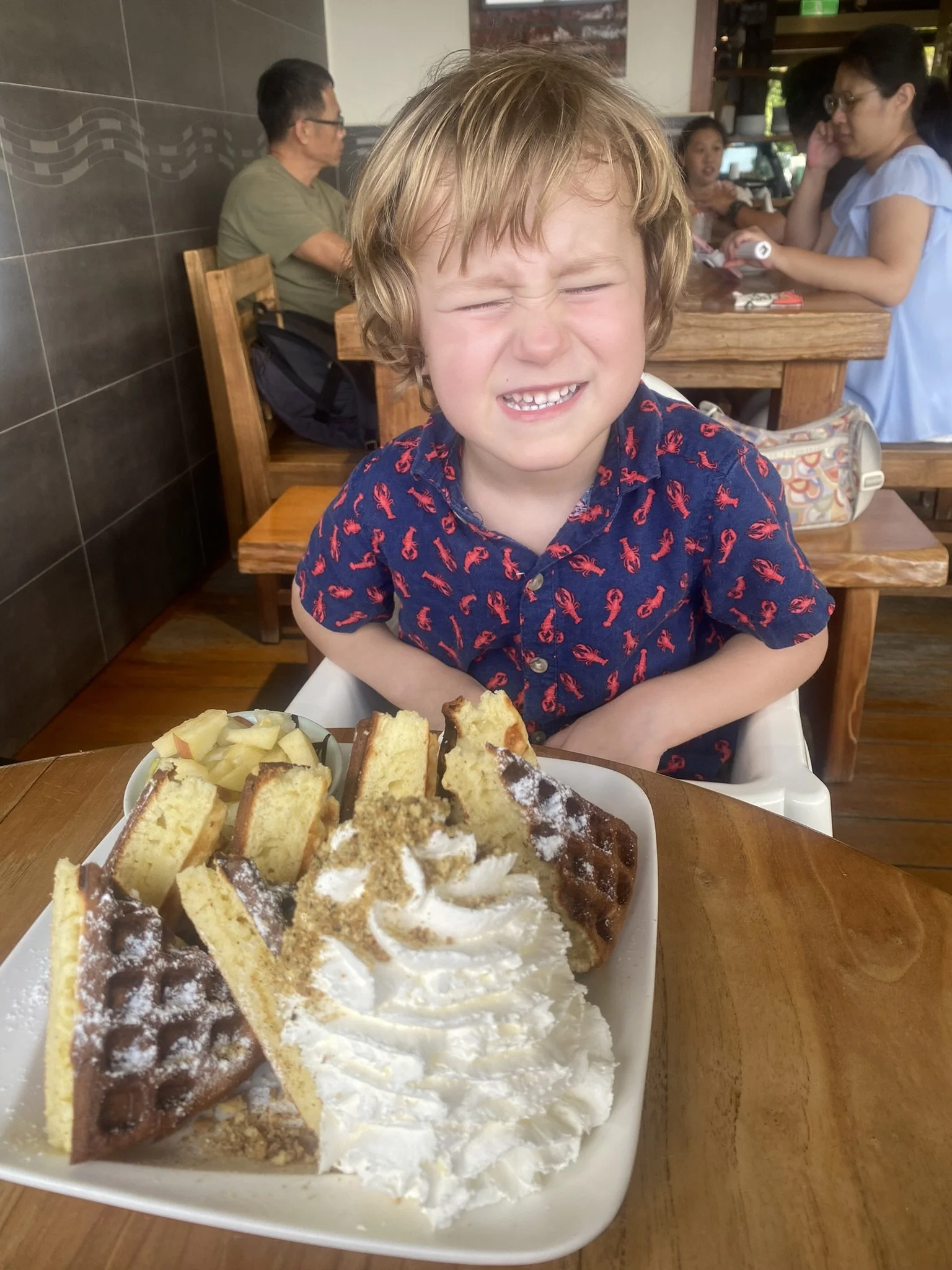 A child smiling over a plate of waffles at a Maokong tea house.