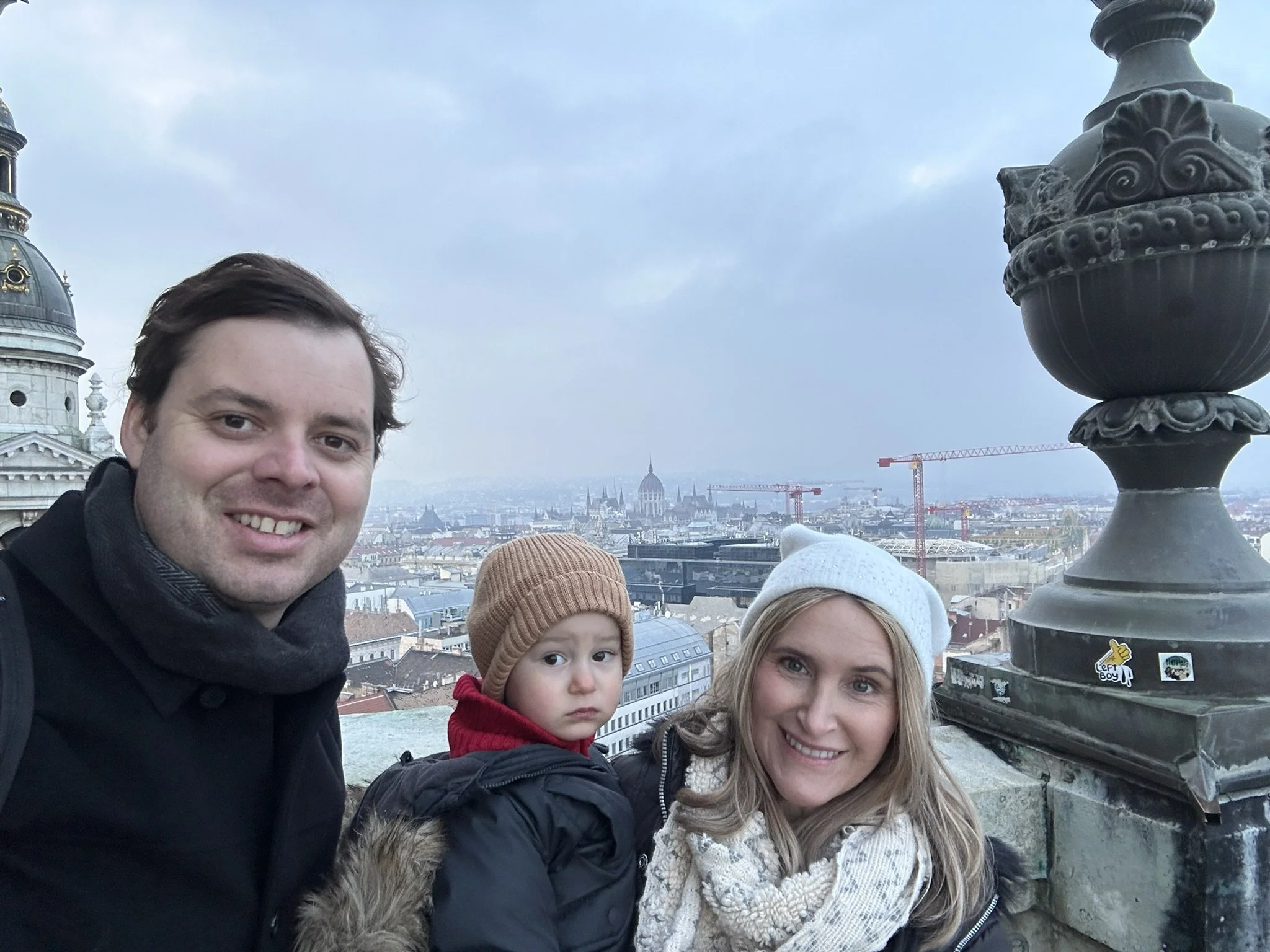 Family of three taking a selfie from the observation deck of St. Stephen’s Basilica in Budapest.