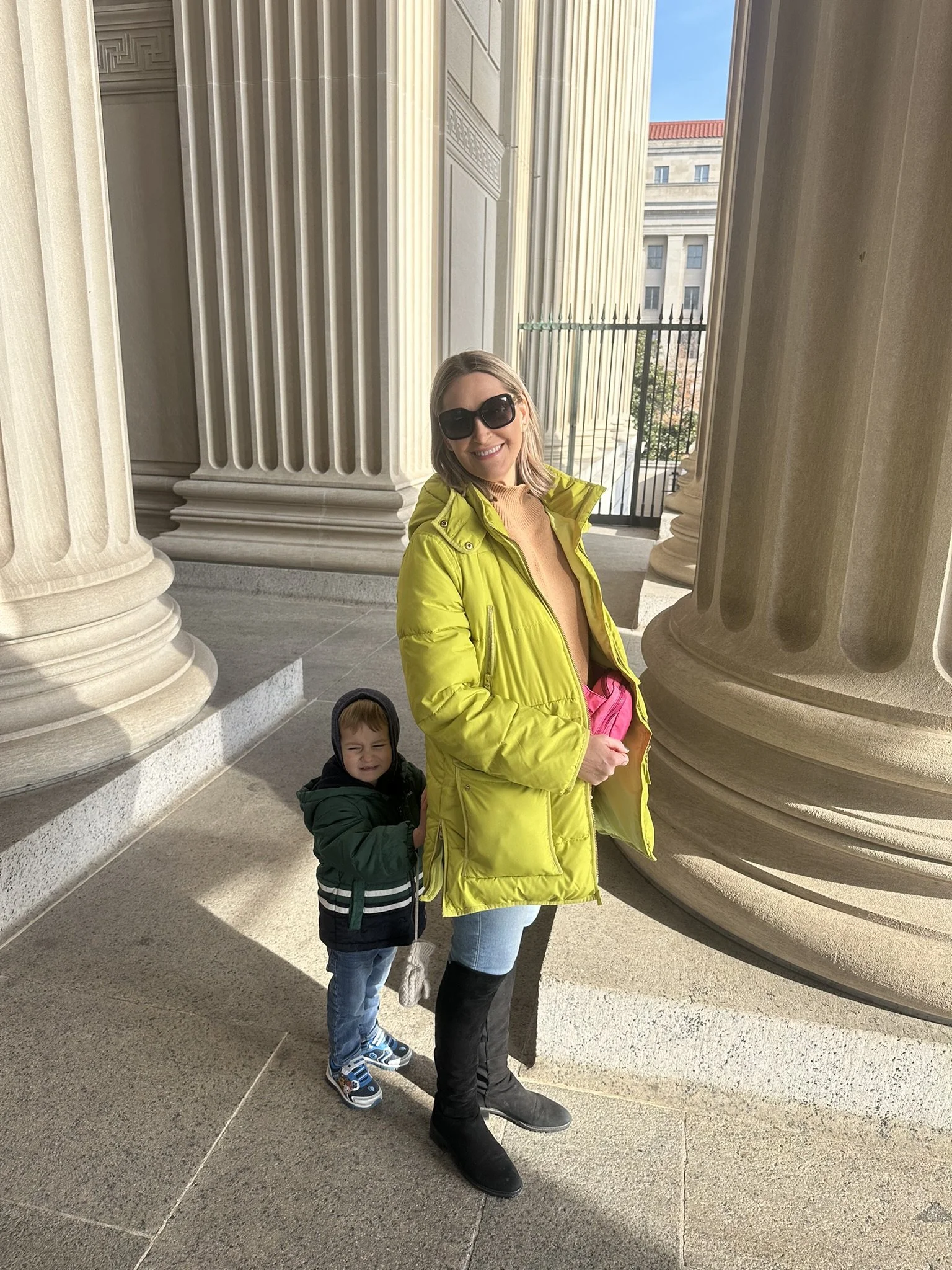Woman and young boy standing beside tall stone columns in Washington, DC.