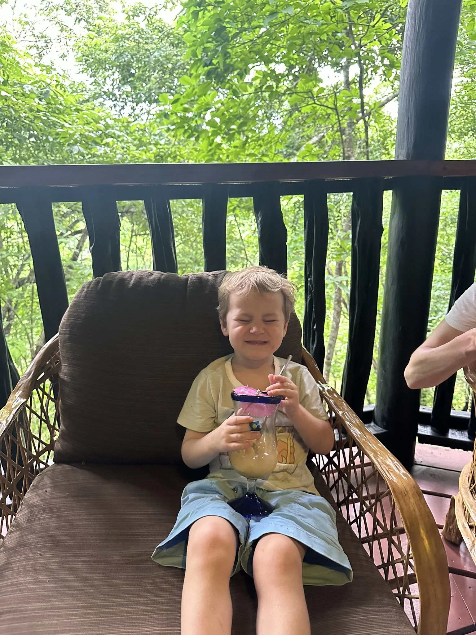 Young boy relaxing with a smoothie on a jungle balcony at Table Rock Jungle Lodge in Belize.