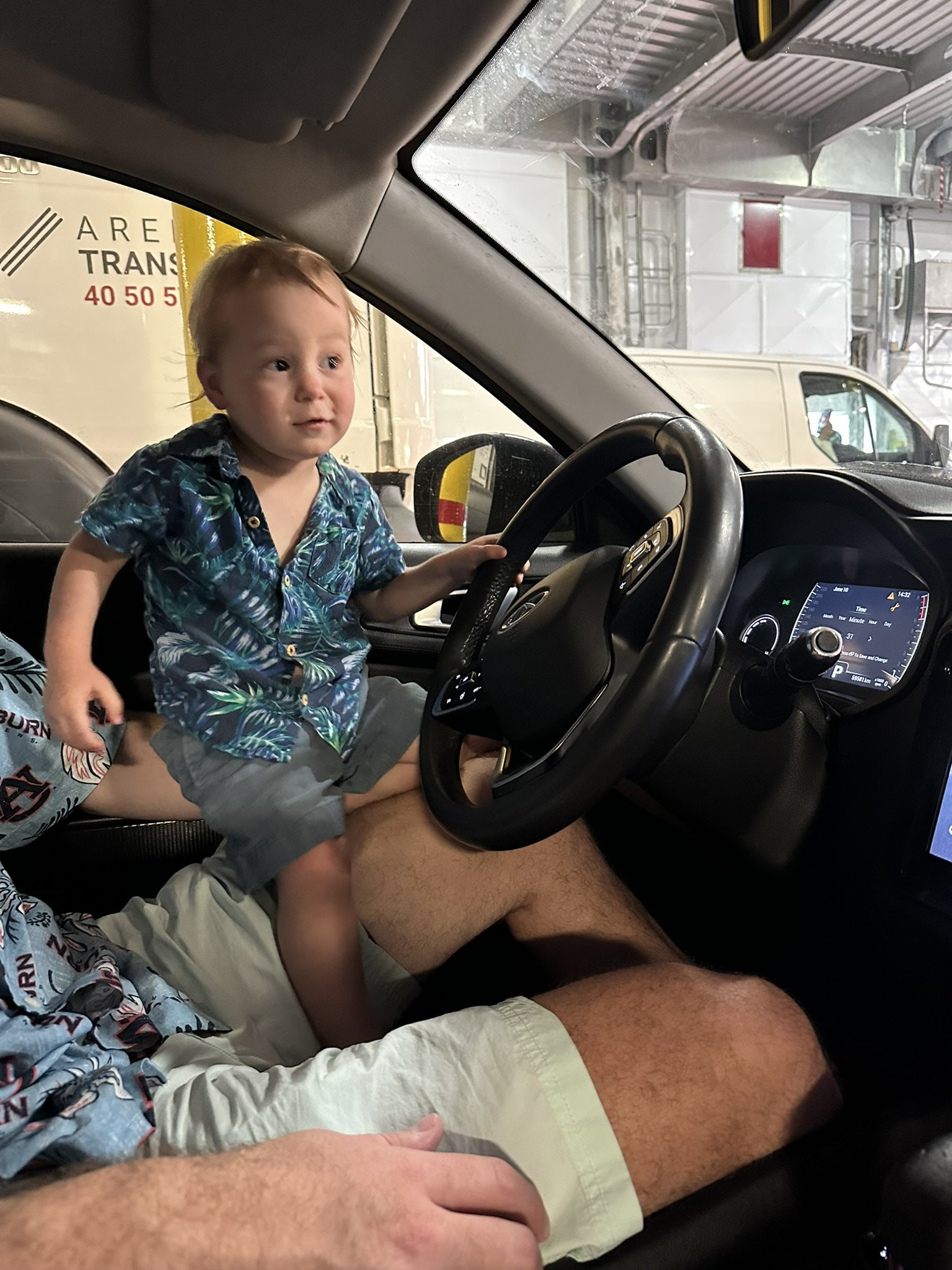 Young child sitting at the wheel of a vehicle aboard the ferry from Moorea to Tahiti.