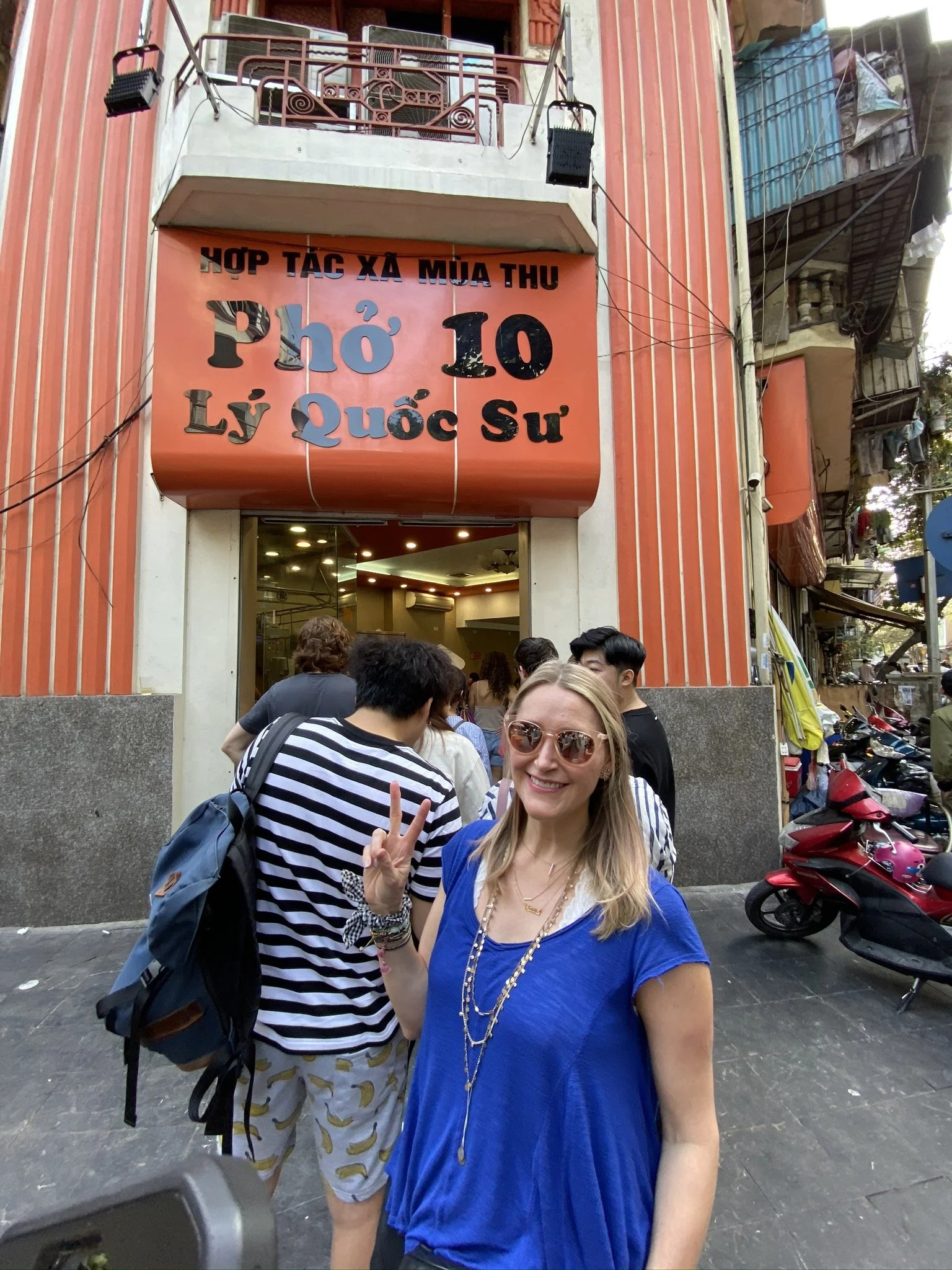 Woman outside a busy pho restaurant on a street in Hanoi, Vietnam.