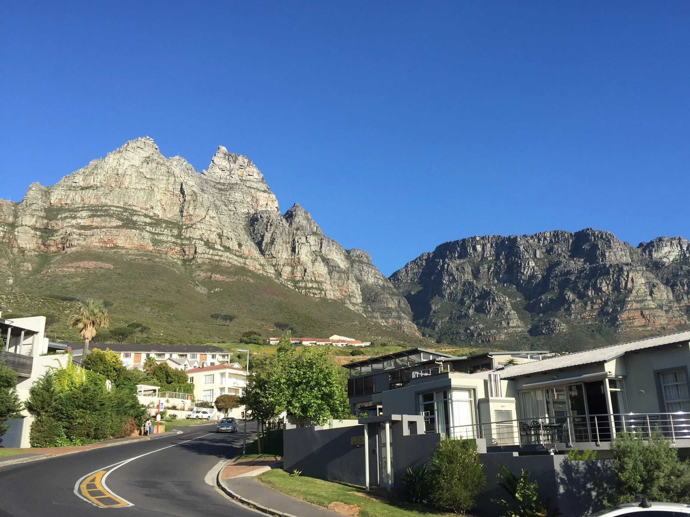 Rocky mountains rise above a winding road and homes in Cape Town.