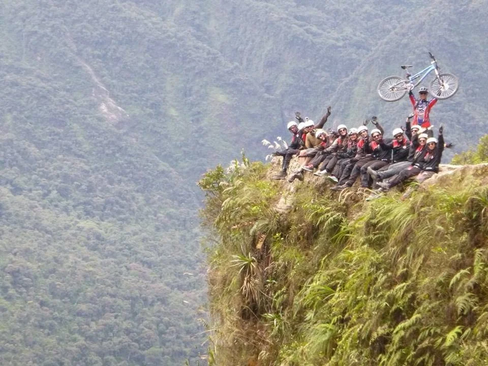 Cyclists posing with their bikes at a mountain overlook during a Death Road tour in Bolivia.