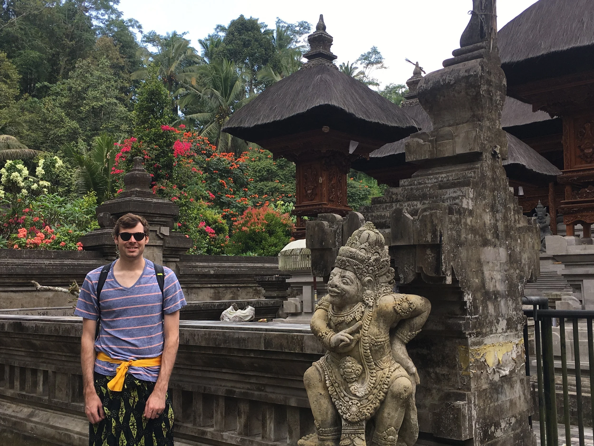 A person standing beside carved stone figures at a Balinese temple near Ubud.
