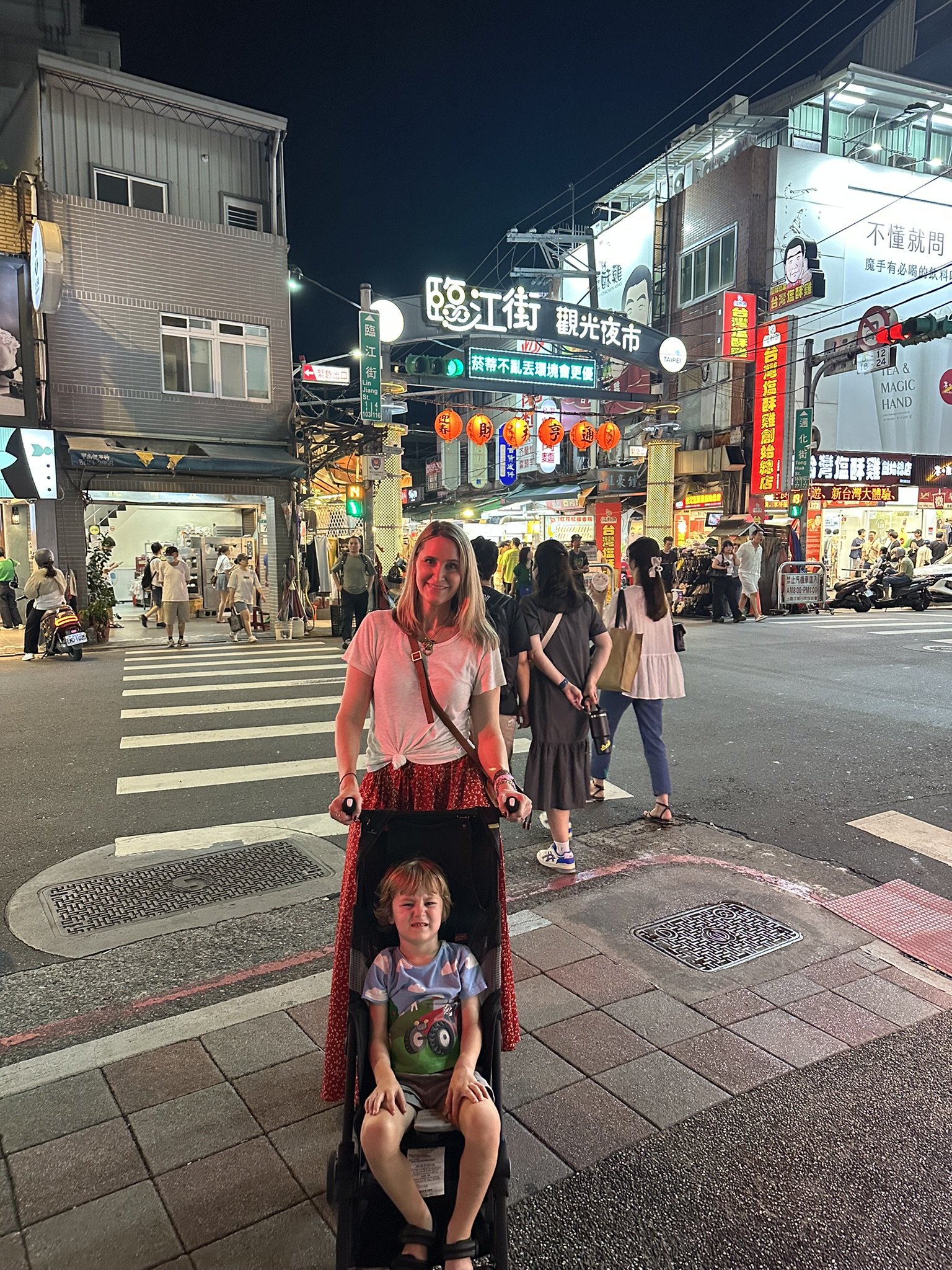 1. An adult with a child in a stroller at a busy Taipei night market.