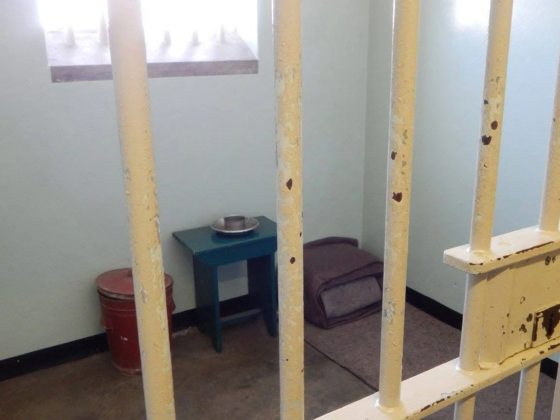 Nelson Mandela’s former prison cell on Robben Island, seen through its barred doorway.