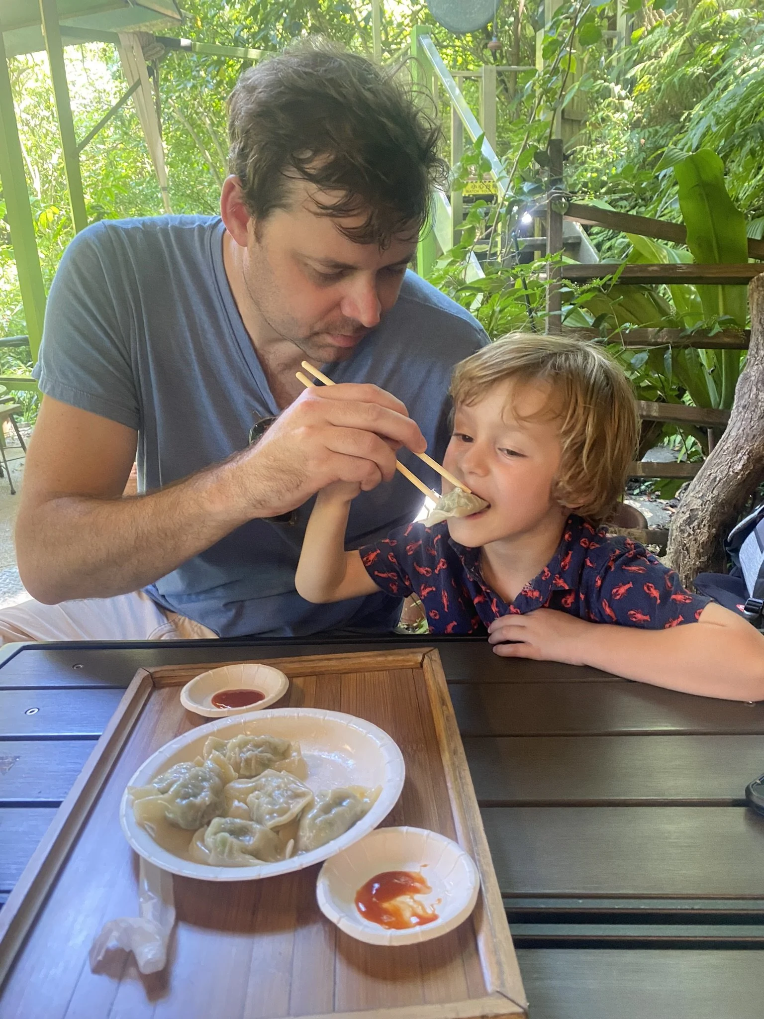 An adult and a child eating dumplings at an outdoor tea house in Jiufen.
