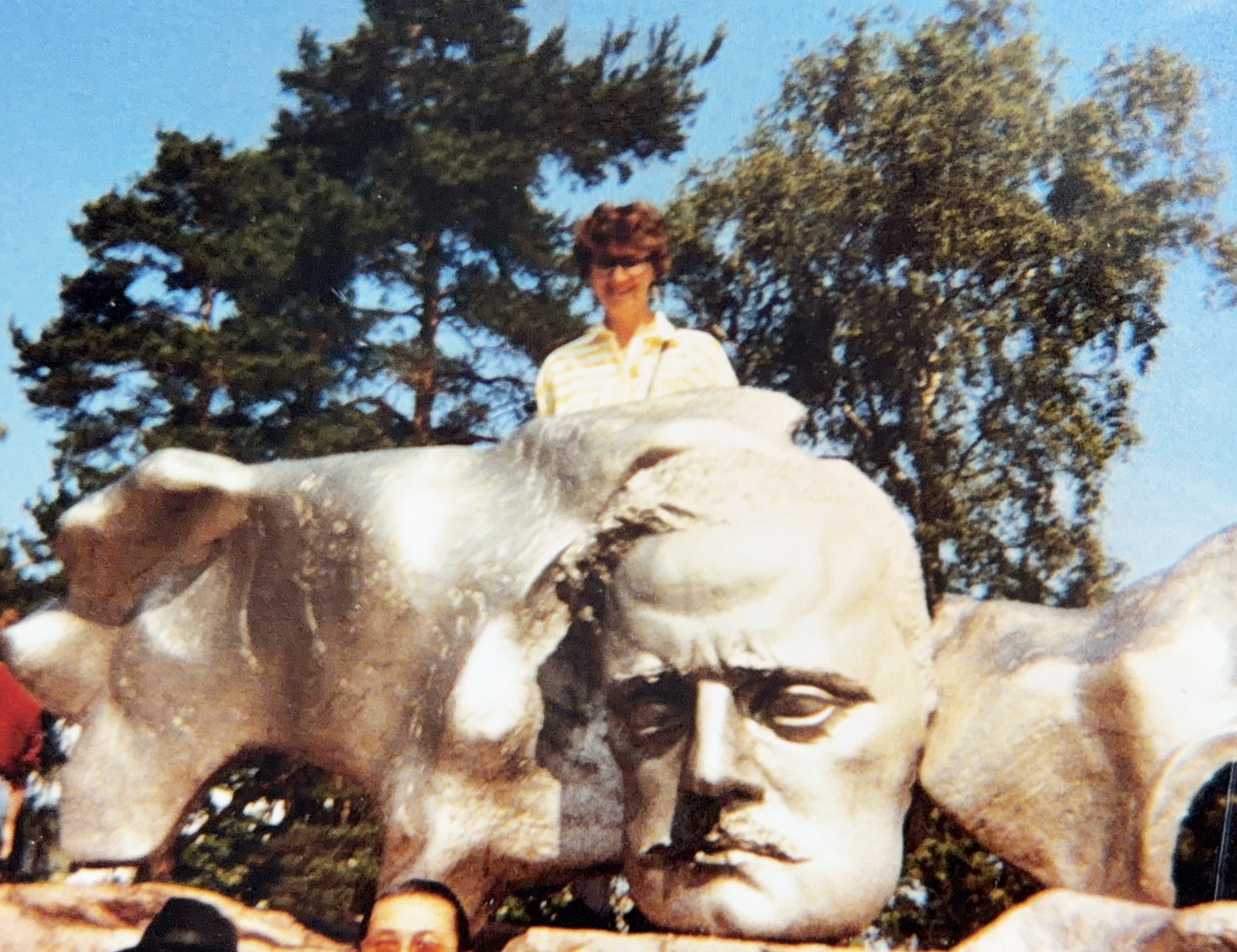 Woman standing behind a sculpted portrait of Jean Sibelius at the Sibelius Monument in Helsinki.