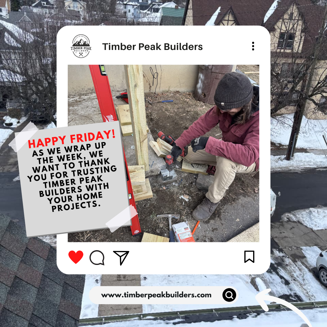 A person wearing a maroon jacket, beige pants, and a black beanie is kneeling on the ground, working on a wooden construction project outside during winter, with snow visible on the ground and rooftops in the background. They are using a power tool o