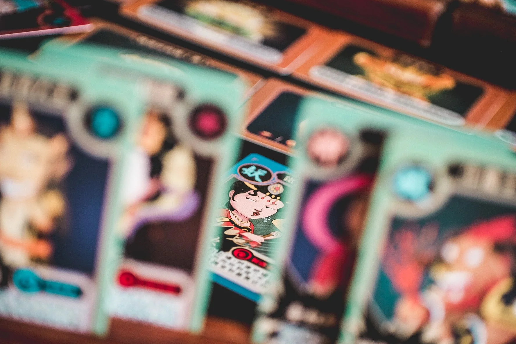 Close-up of several colorful playing cards featuring illustrations of characters, some with traditional Asian attire and makeup, arranged in a spread.