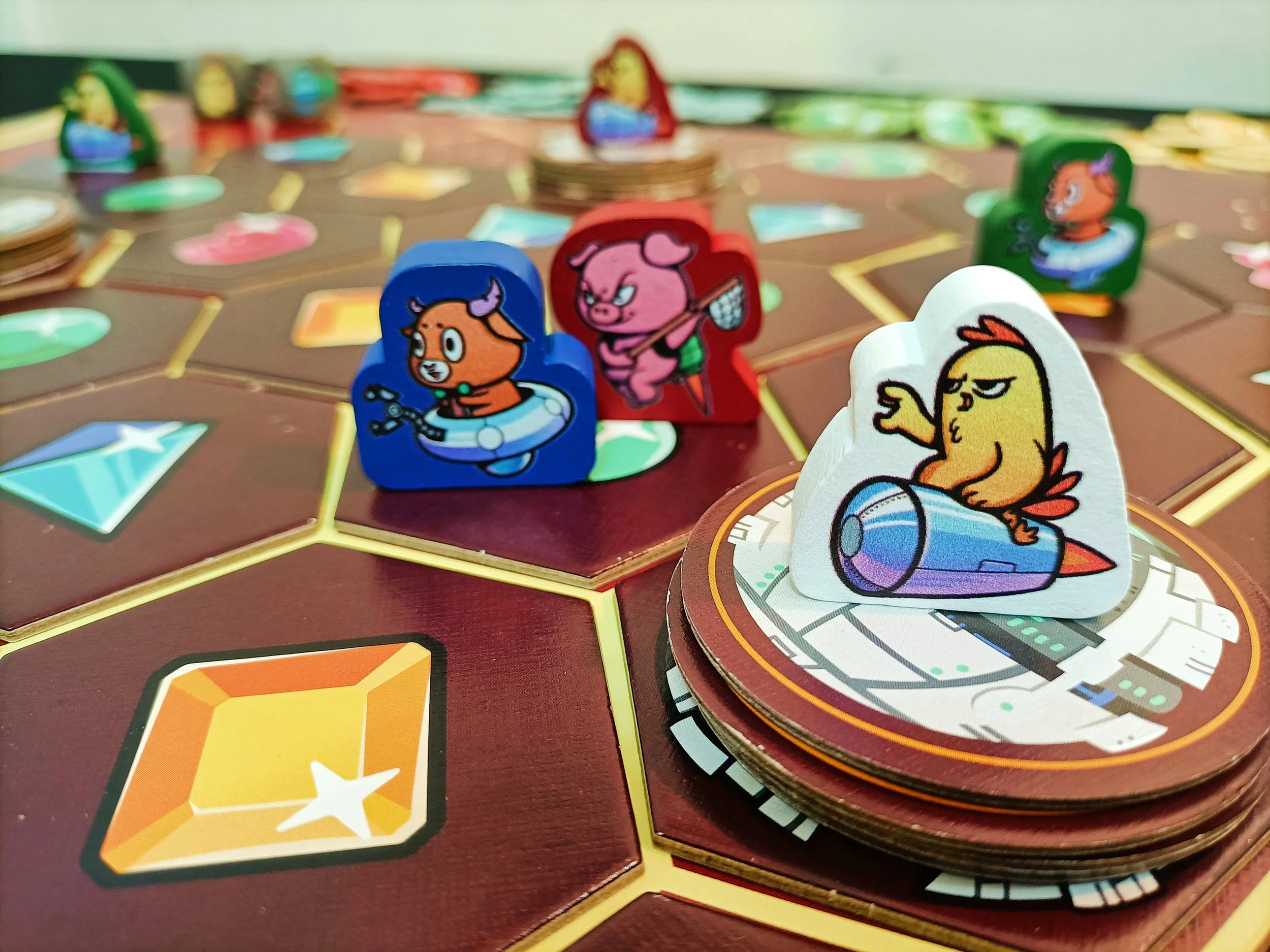Close-up of a board game with colorful player pieces featuring cartoon animals, including a pig, a chick, and a dog, on a game board with hexagonal spaces and tokens in the background.