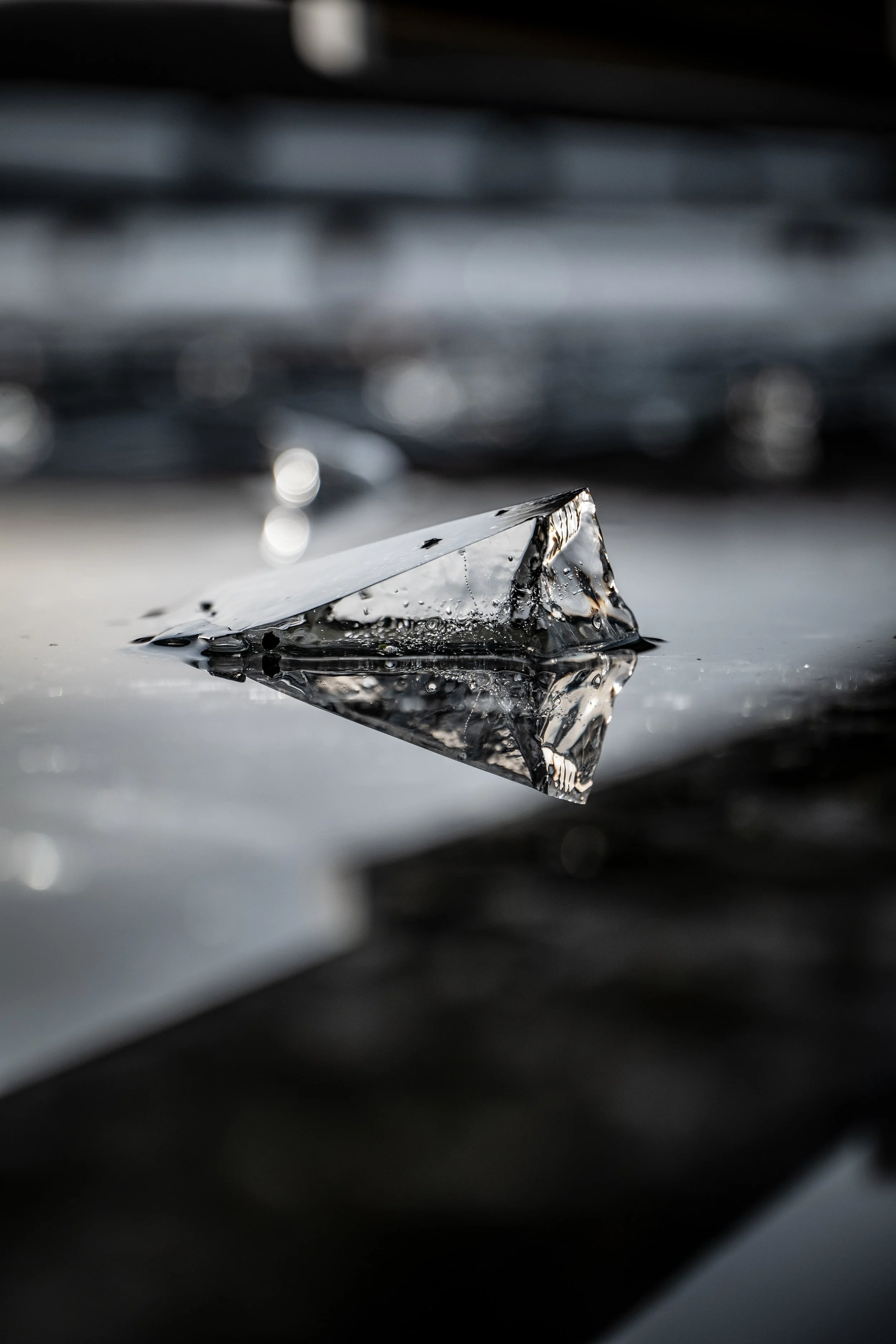 Close-up of a diamond on a reflective surface with a blurred background.