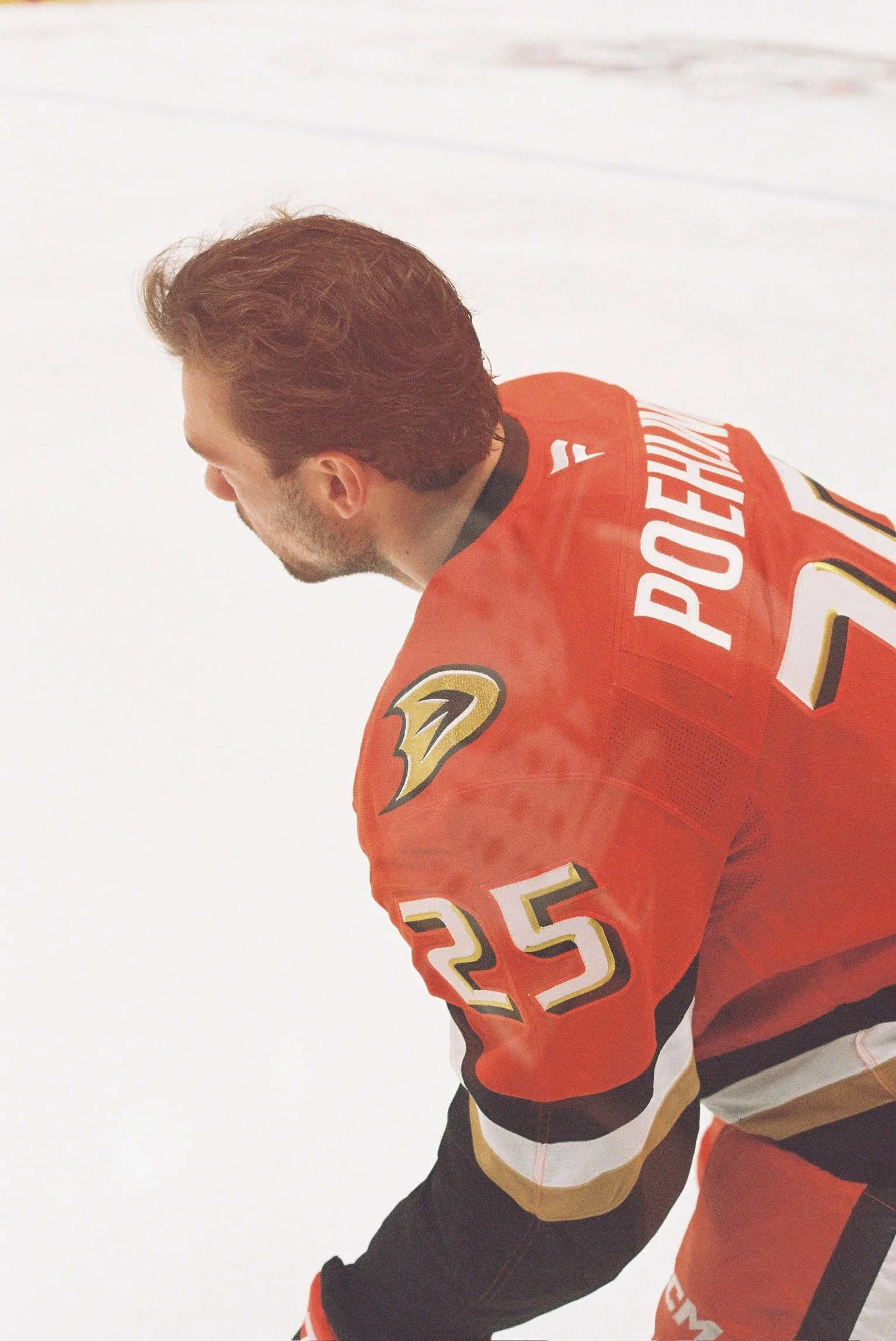 Close-up of a hockey player in an orange Anaheim Ducks jersey with the number 25, viewed from the side, on the ice rink.