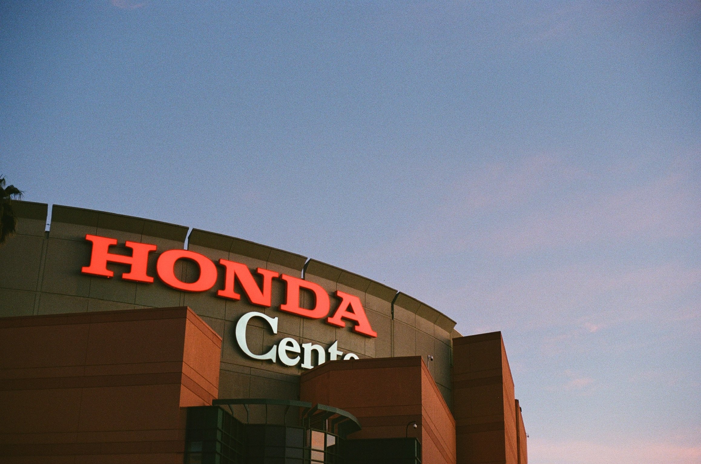 Part of the Honda Center with the letters illuminated and a blue sky behind.