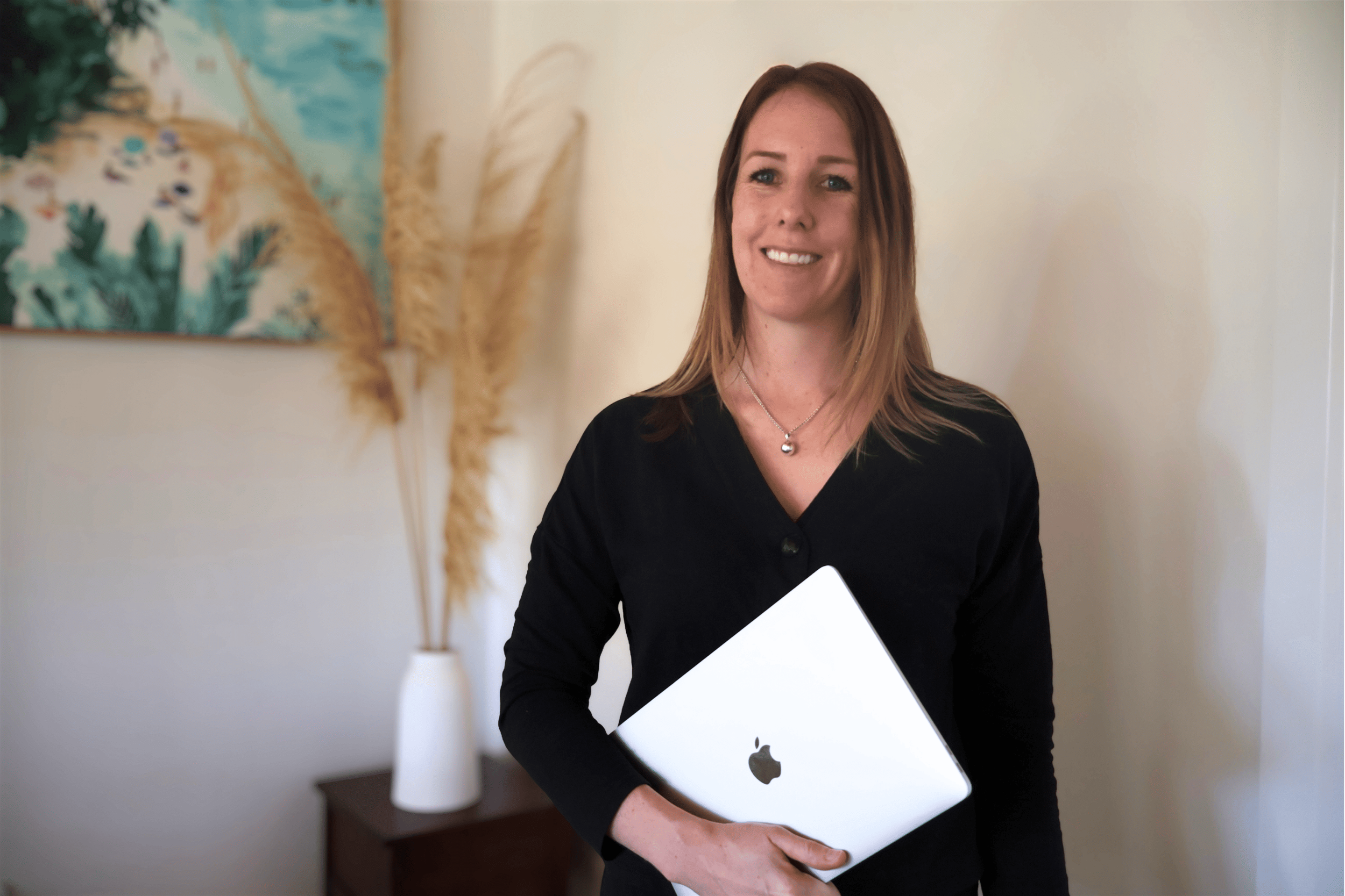 Hawke's Bay web designer Hayley from Innerbloom Studio holding MacBook laptop