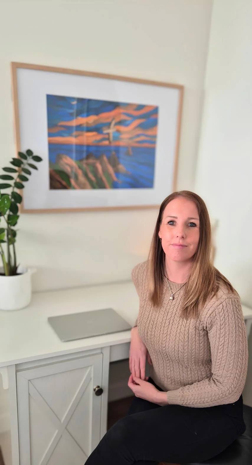 Hayley from Innerbloom Studio sitting in her home office where she designs websites for small businesses.