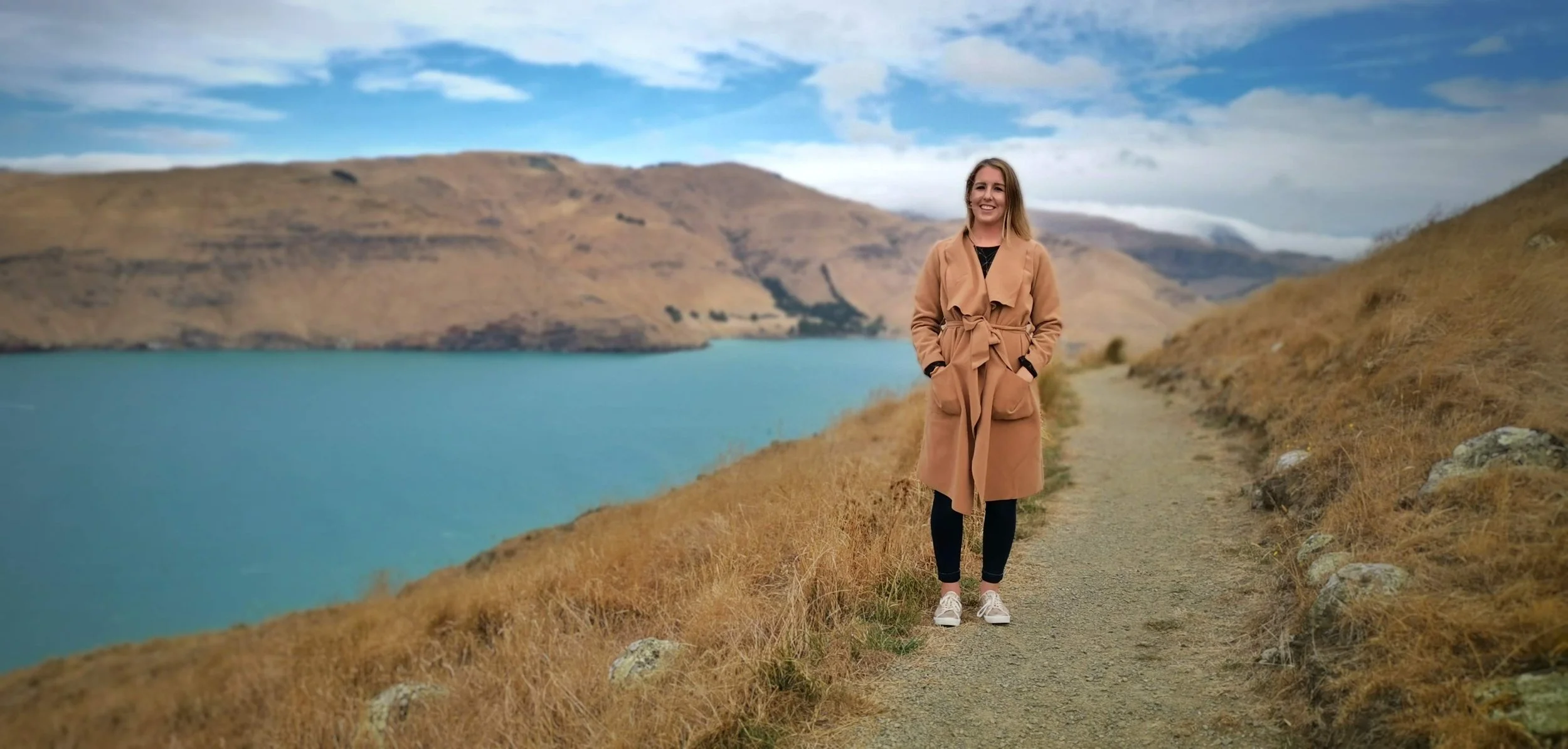 Hayley walking the coastal track at Godley Head, Christchurch, part of the New Zealand adventures behind Innerbloom Studio's story.
